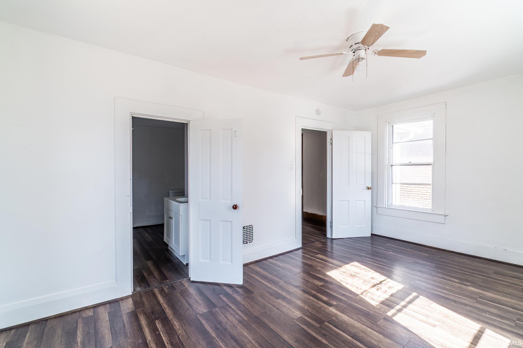 Unfurnished bedroom featuring a ceiling fan and dark wood-type flooring