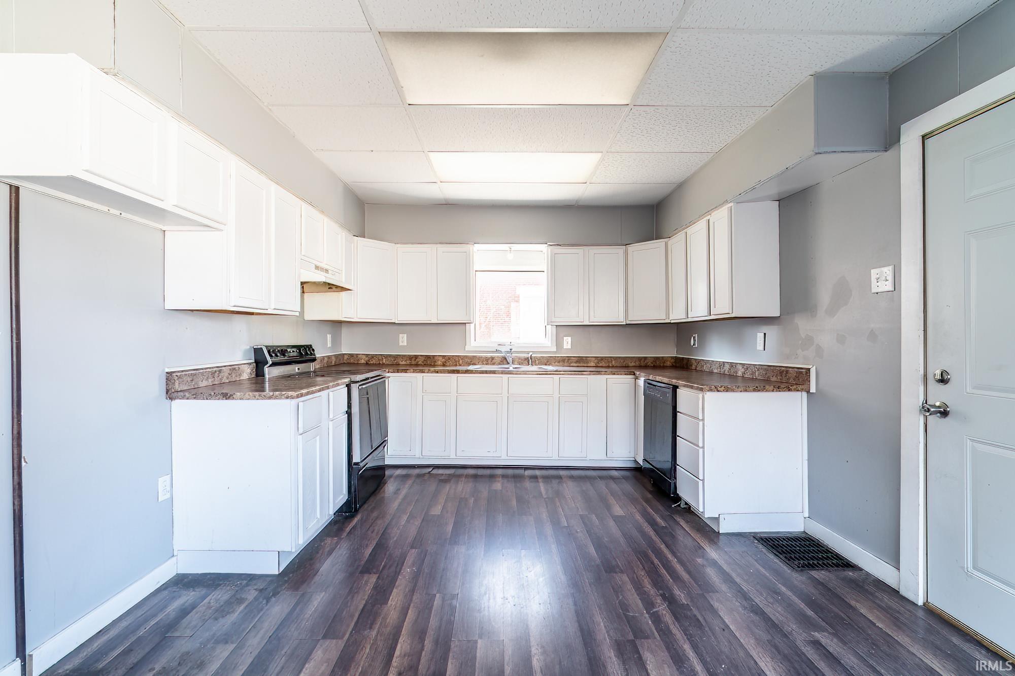 Kitchen featuring dark countertops, white cabinetry, electric range, a drop ceiling, and dark wood-style flooring