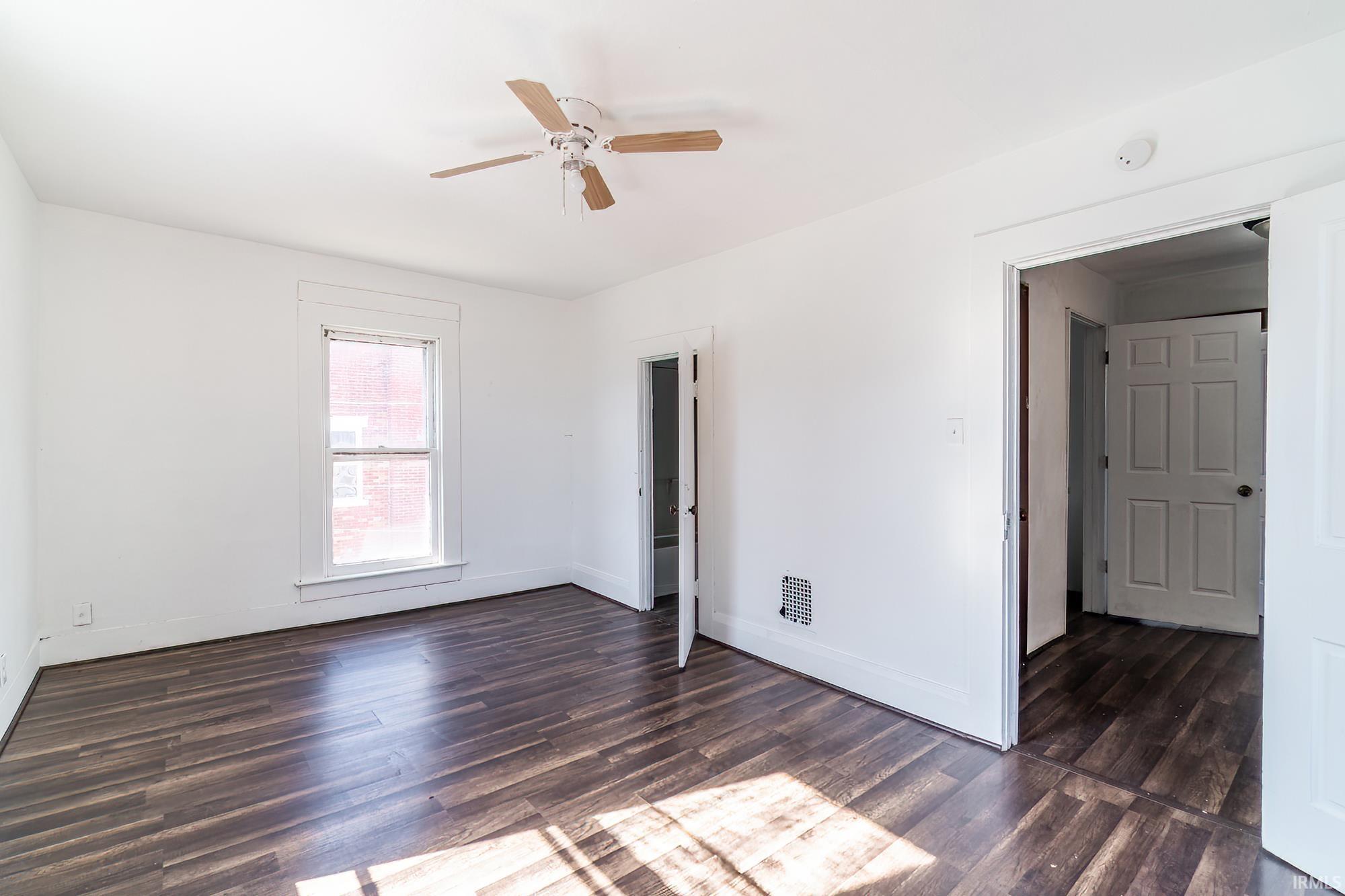 Unfurnished bedroom featuring dark wood-type flooring and a ceiling fan