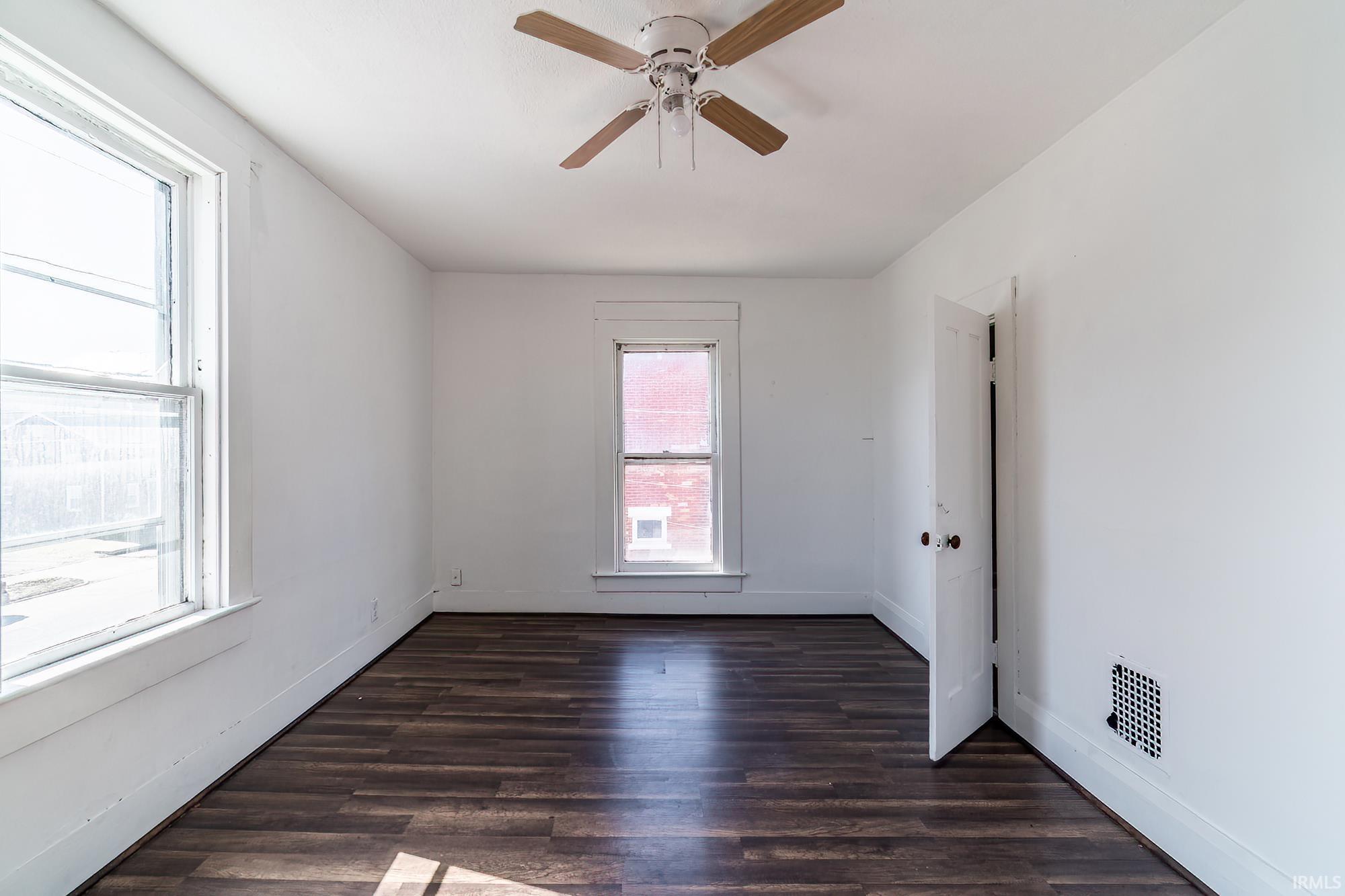 Empty room with dark wood-style floors and ceiling fan