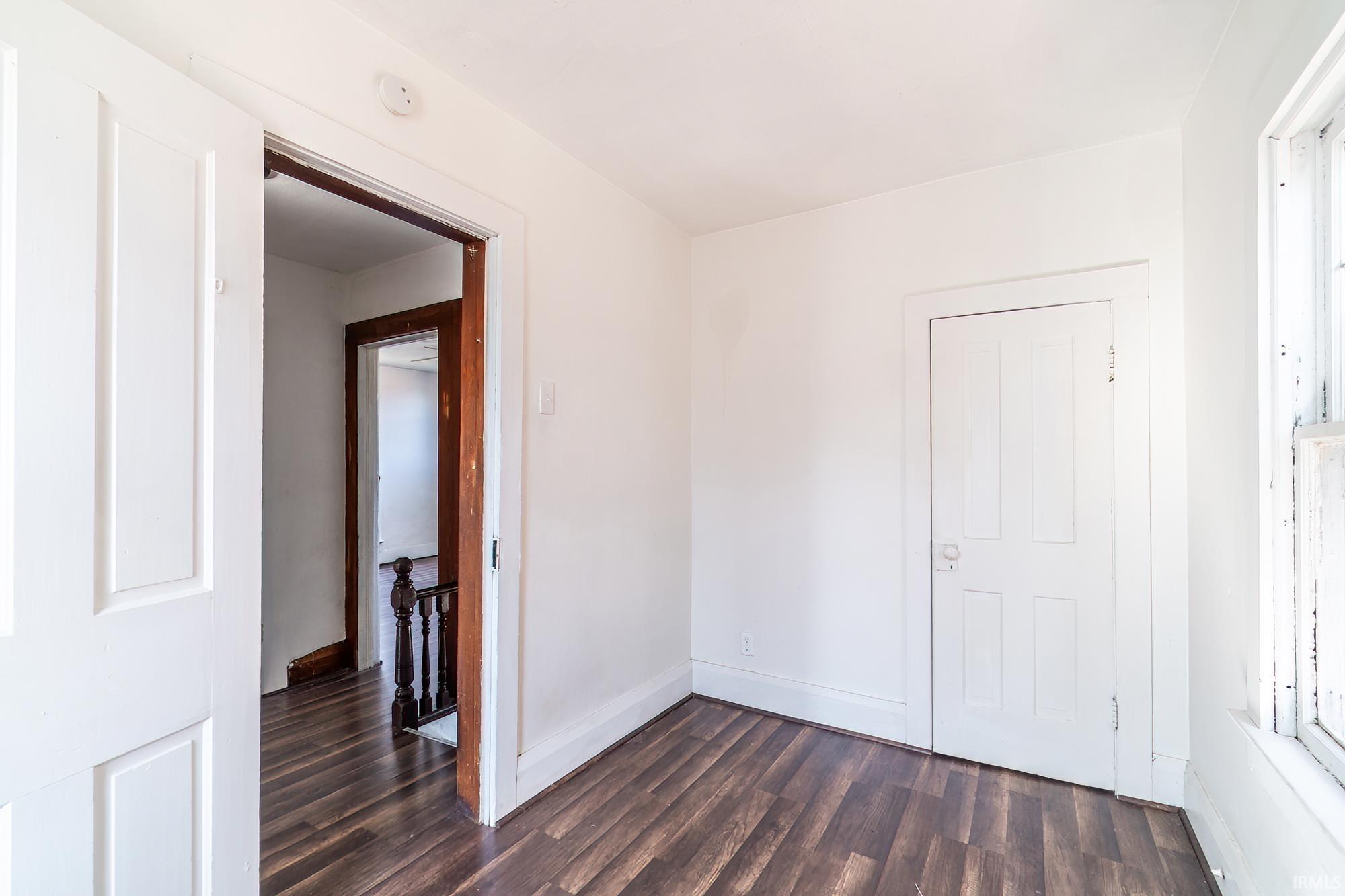 Unfurnished bedroom featuring dark wood finished floors and baseboards