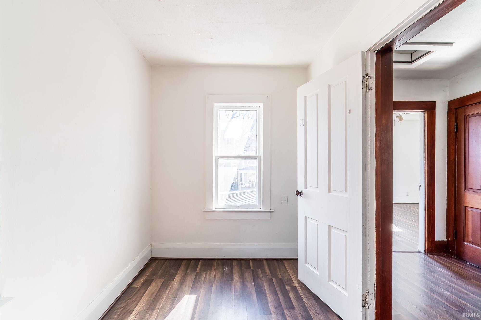 Spare room featuring dark wood finished floors and baseboards
