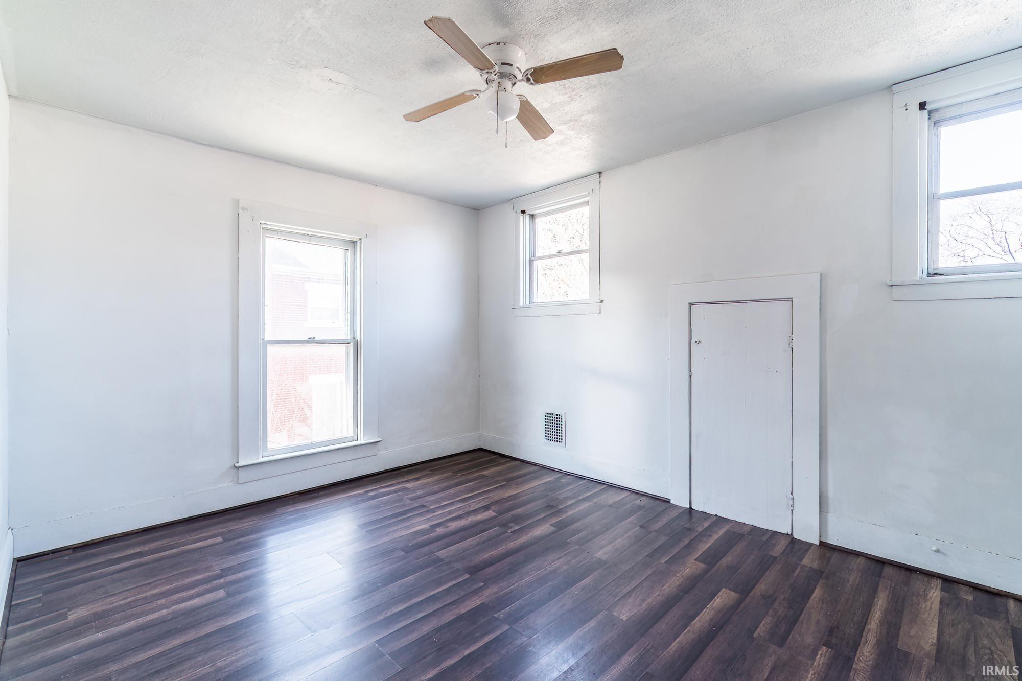 Unfurnished room featuring a ceiling fan and dark wood-style flooring