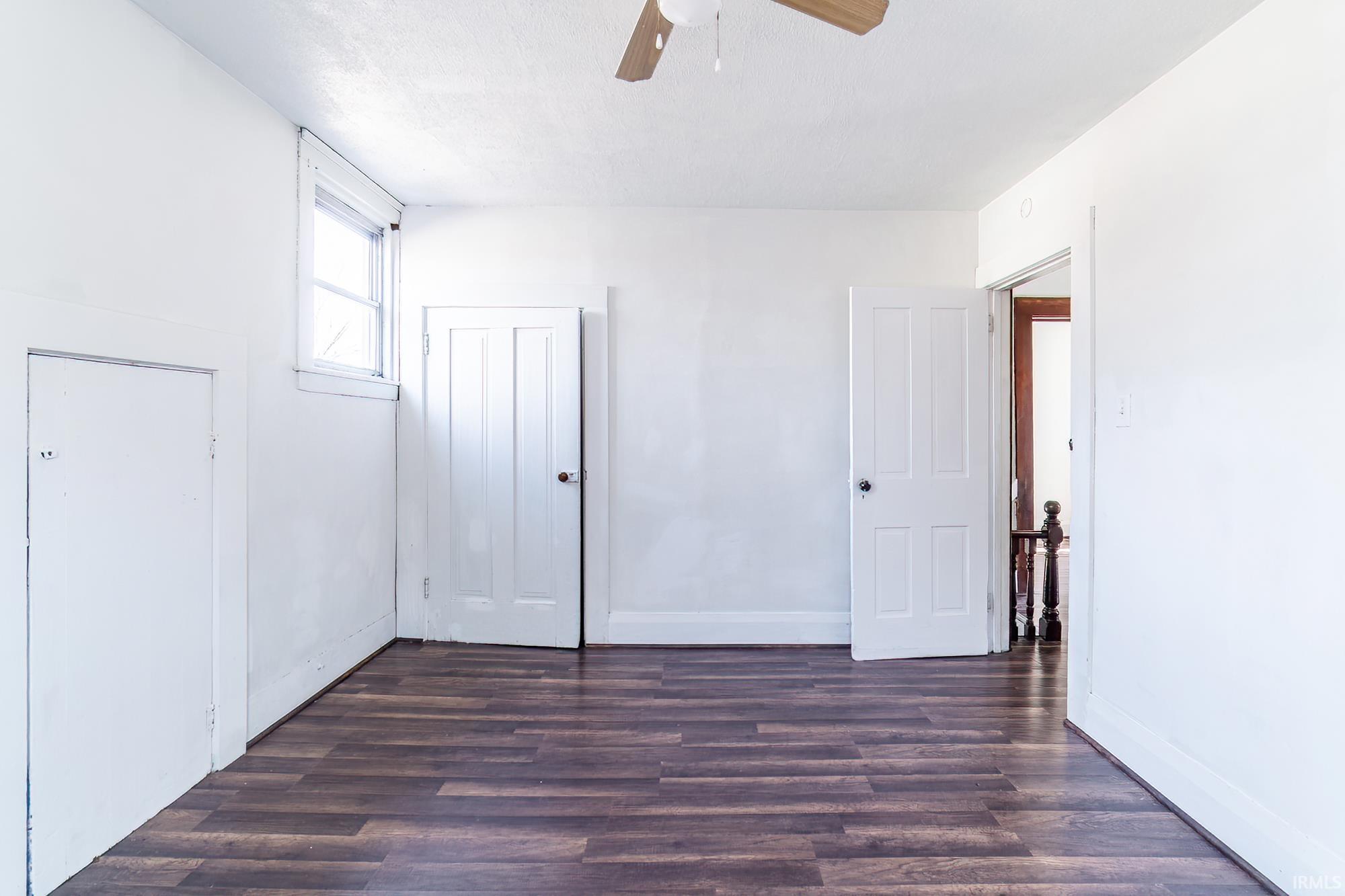 Unfurnished bedroom featuring dark wood-style floors, a ceiling fan, and a closet