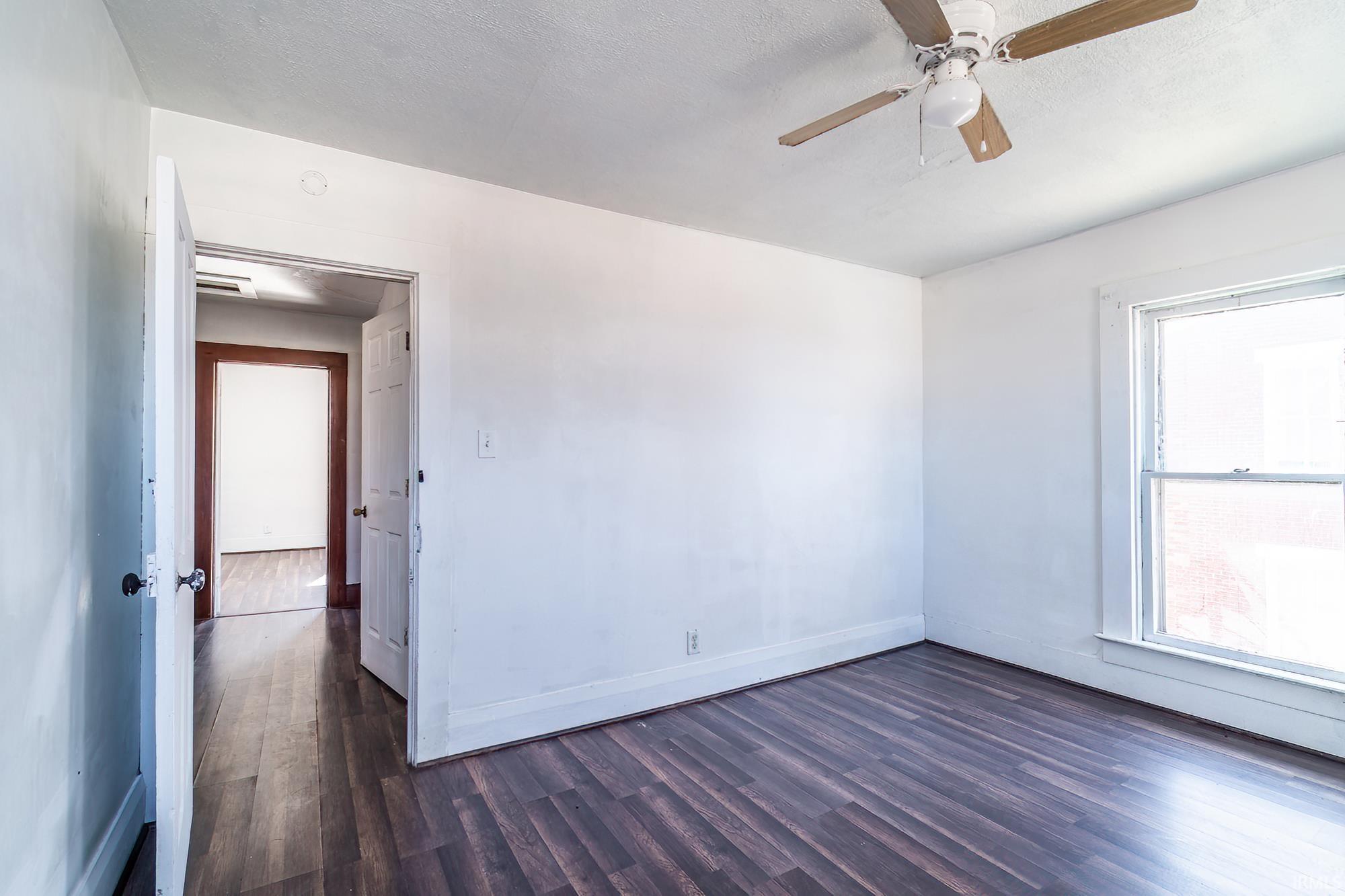 Empty room with dark wood-type flooring, ceiling fan, and a textured ceiling