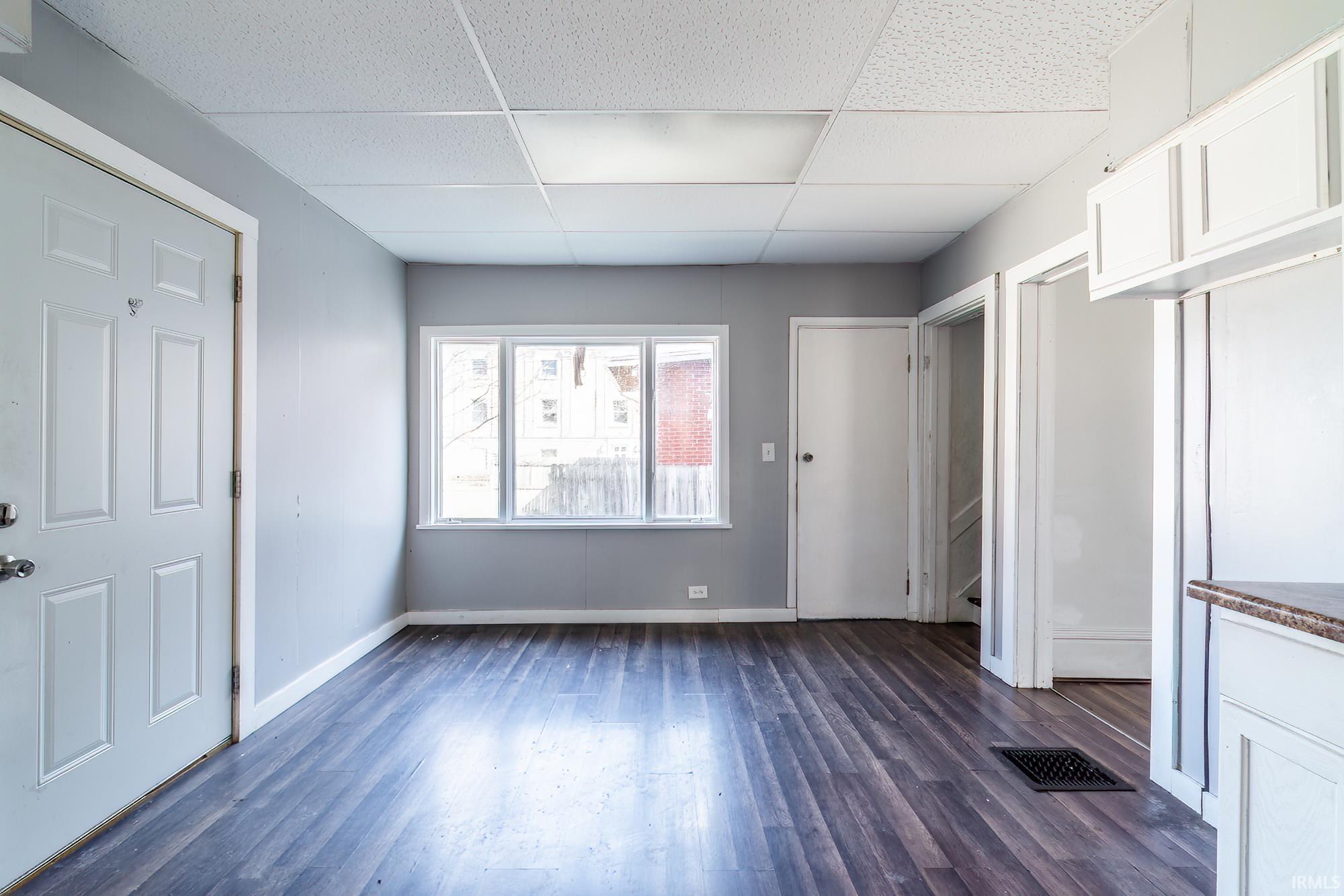 Unfurnished bedroom featuring a paneled ceiling and dark wood-style flooring