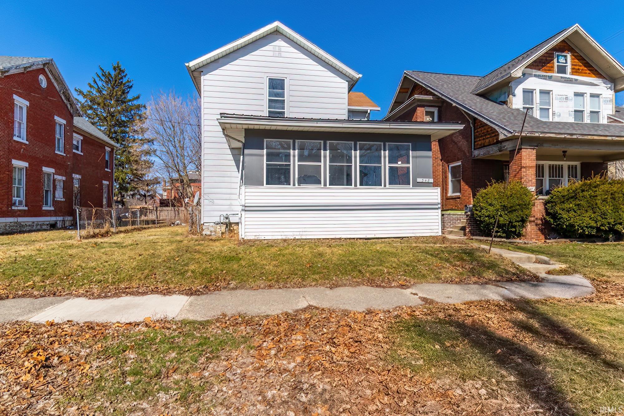 View of front of property with a sunroom and a front lawn