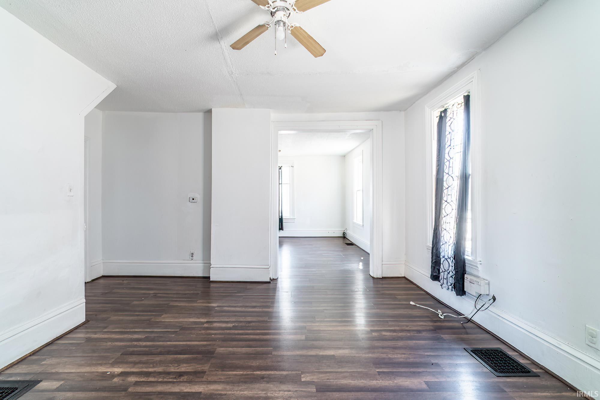Spare room with ceiling fan and dark wood-style floors