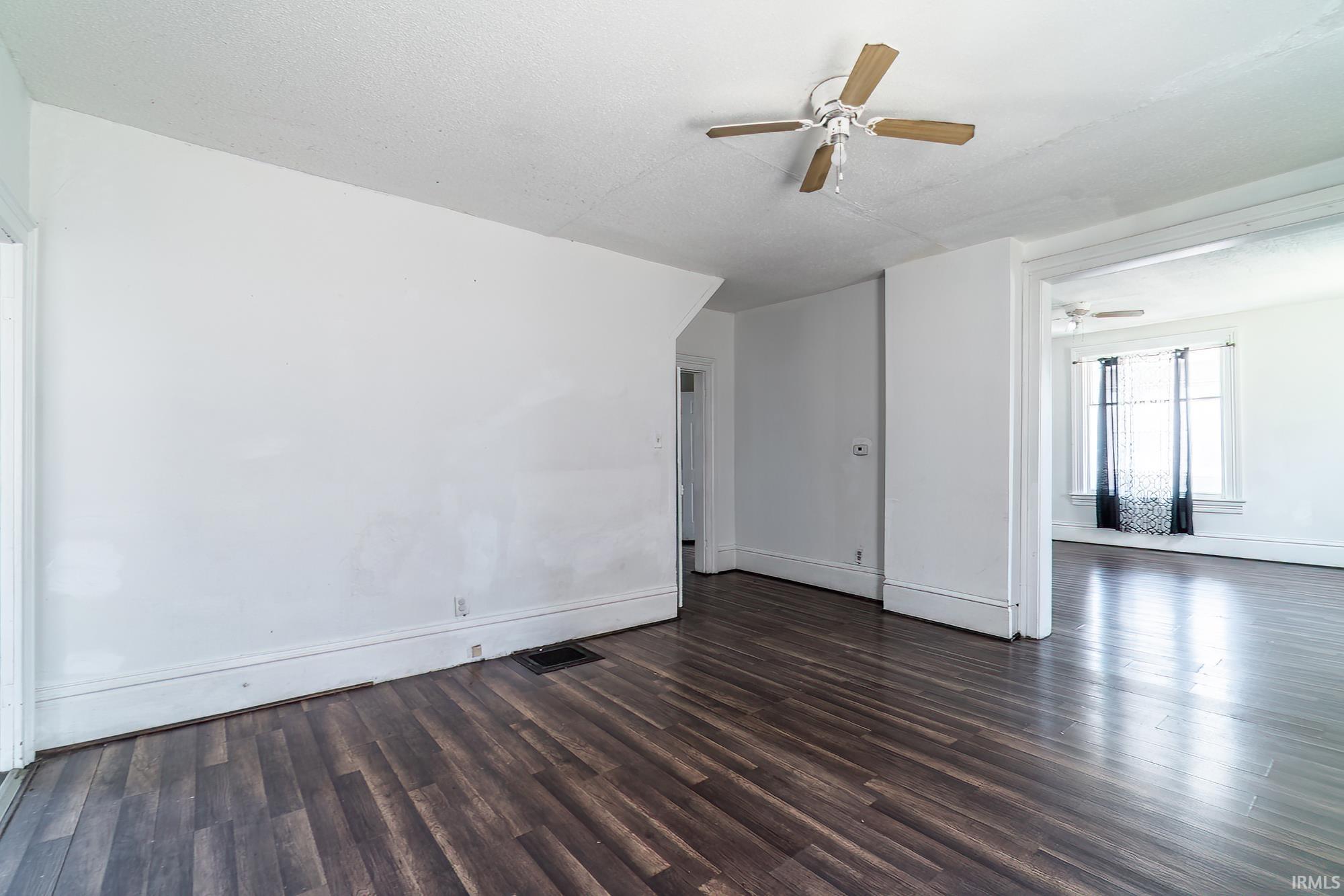 Empty room with dark wood-type flooring and ceiling fan