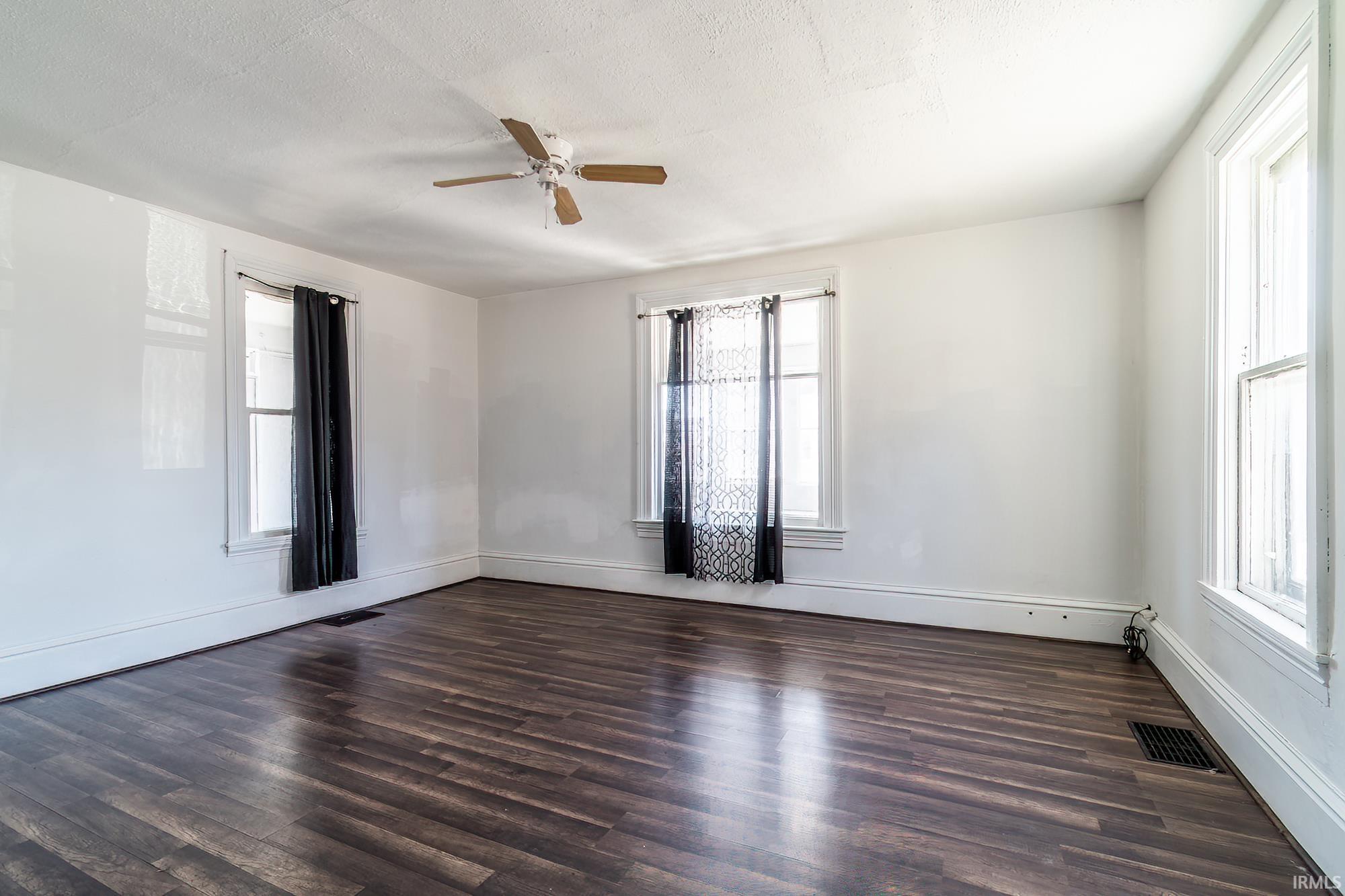 Unfurnished room featuring dark wood-style floors, a ceiling fan, and a textured ceiling