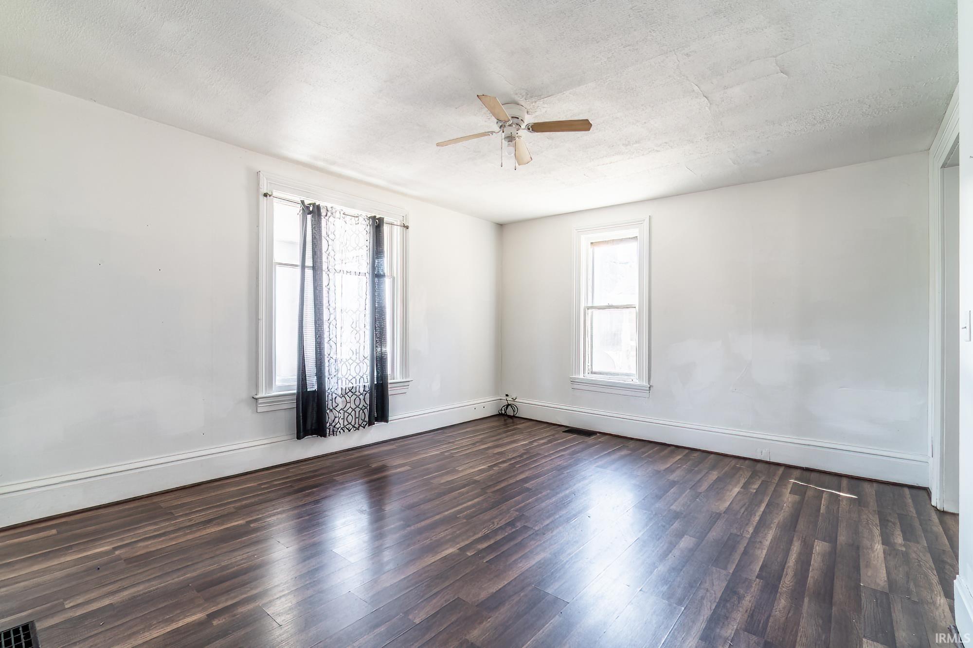 Spare room with dark wood-style floors, a ceiling fan, and a textured ceiling