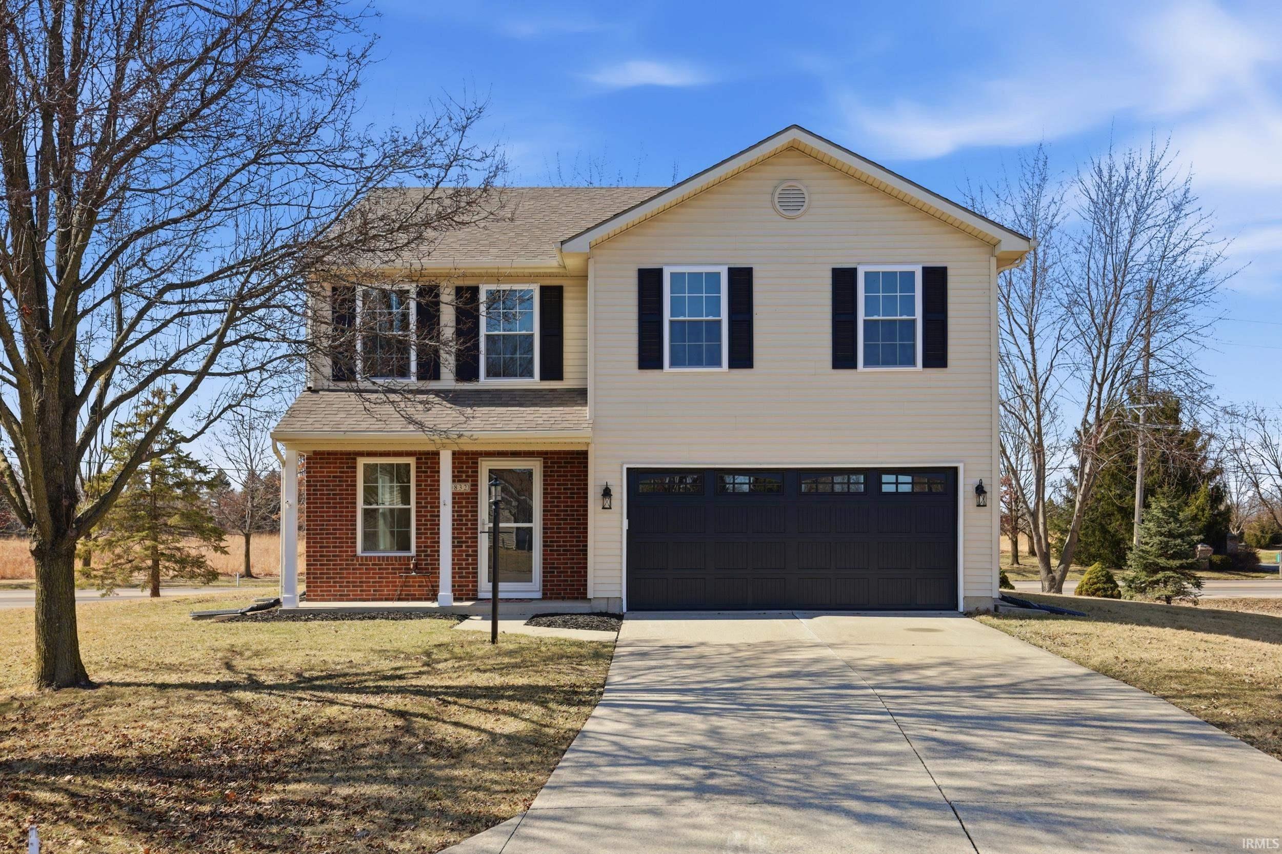 View of front of property with driveway, a porch, roof with shingles, an attached garage, and brick siding
