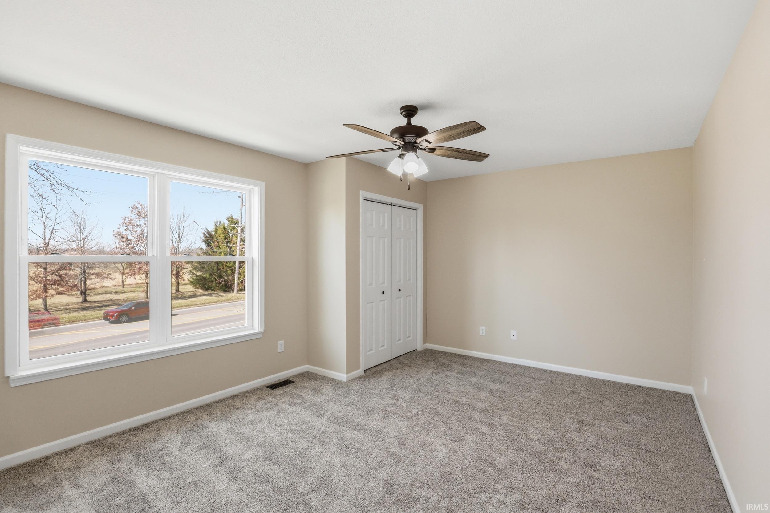 Unfurnished bedroom featuring light colored carpet, a ceiling fan, and a closet