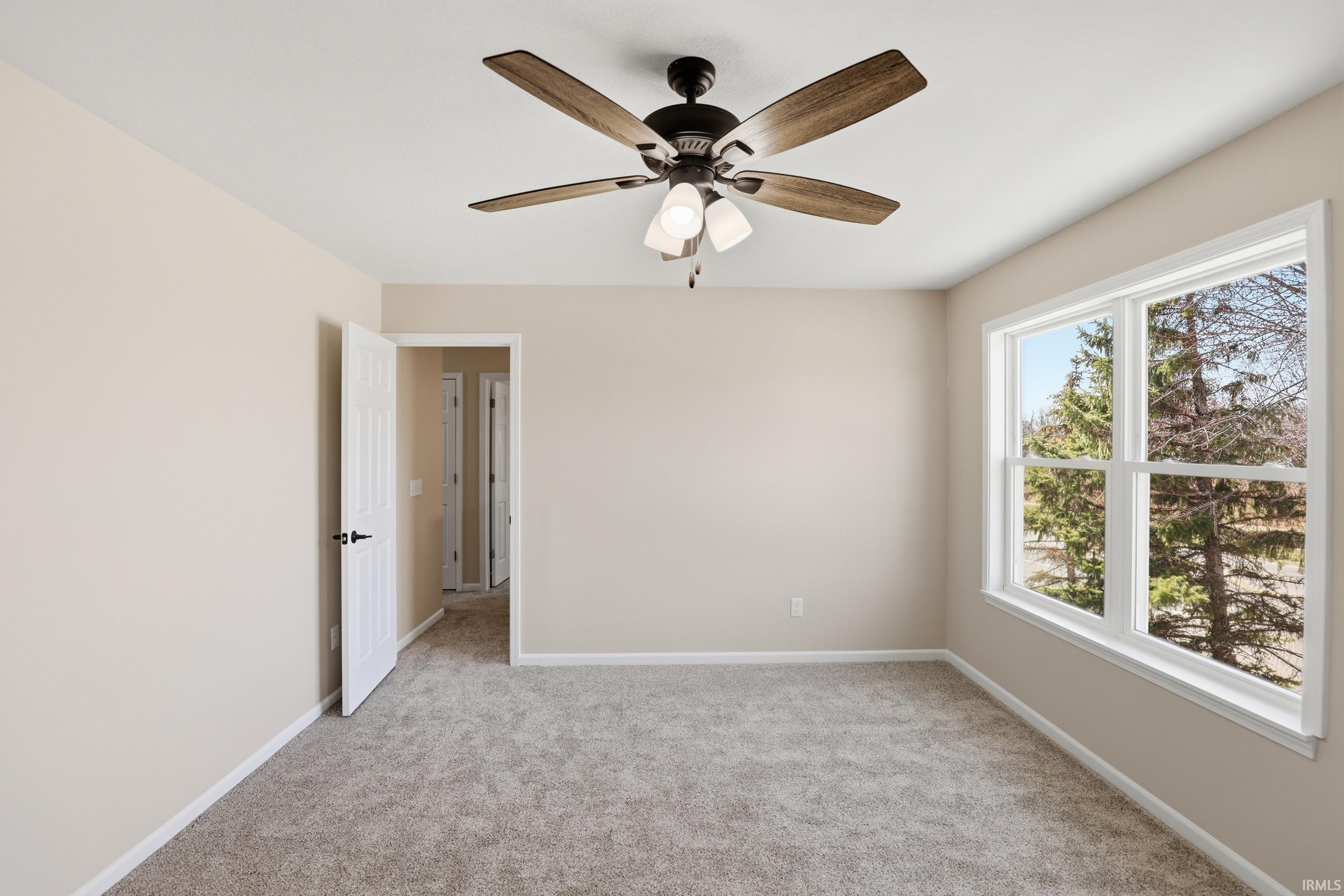 Spare room with light carpet and a ceiling fan