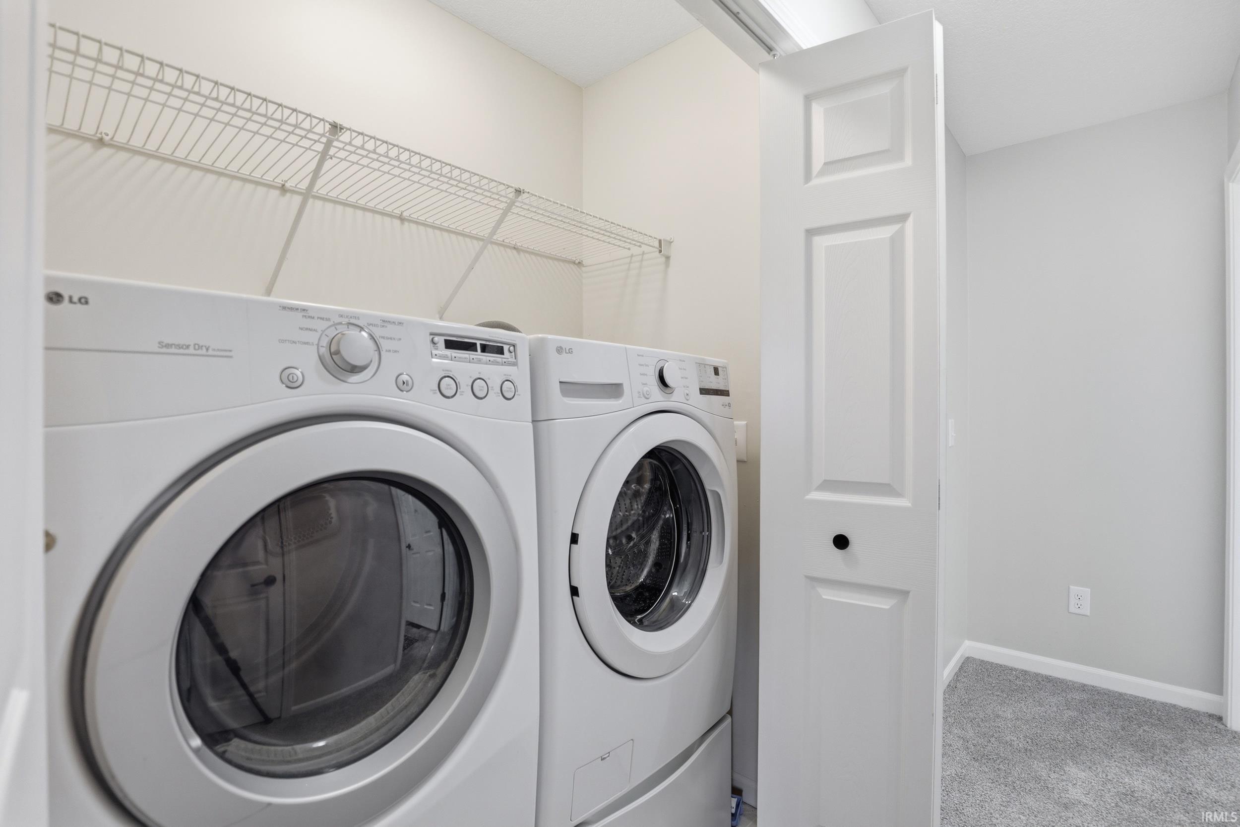 Laundry area with light carpet and washer and dryer