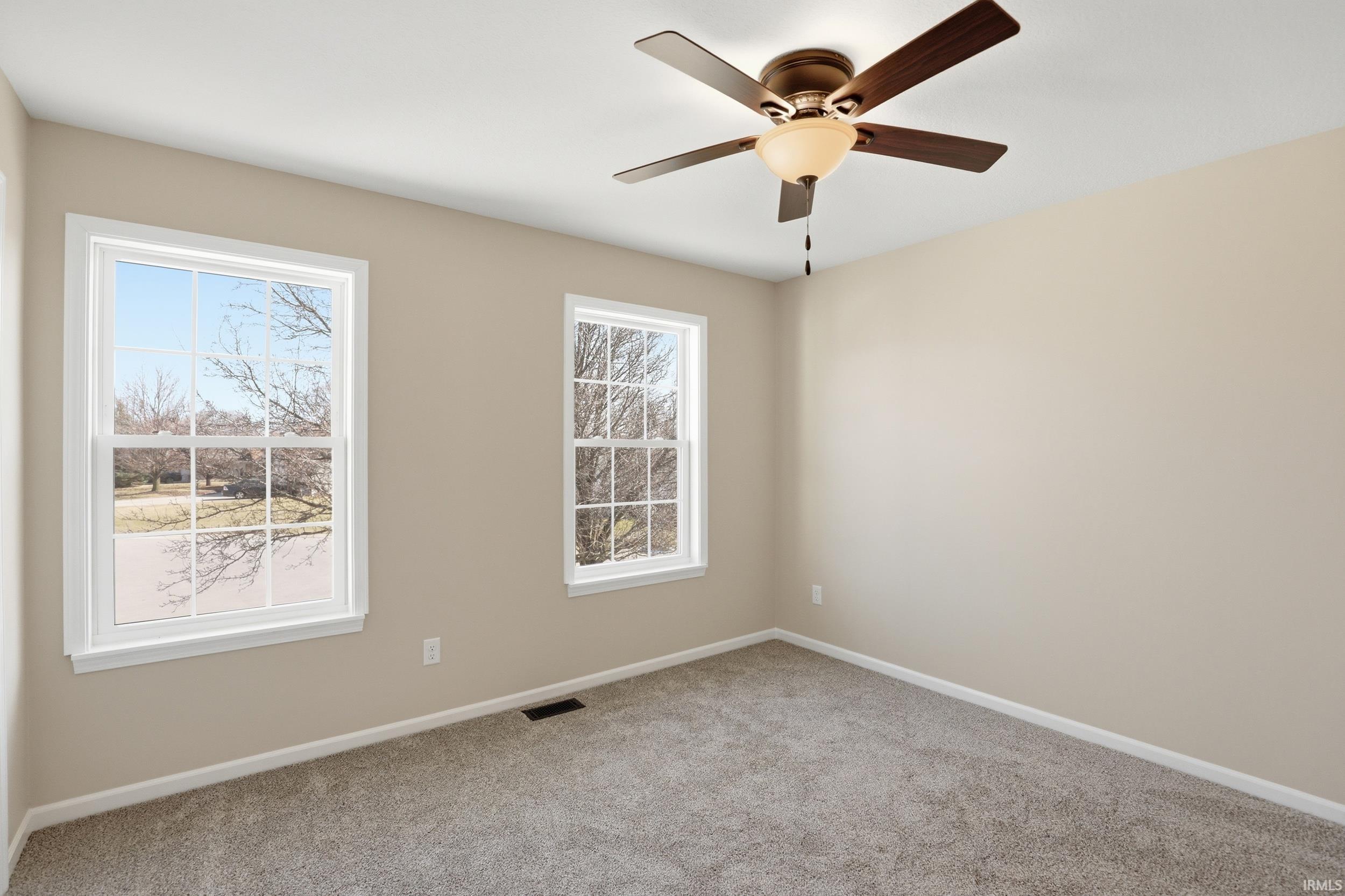 Empty room featuring light colored carpet and a ceiling fan