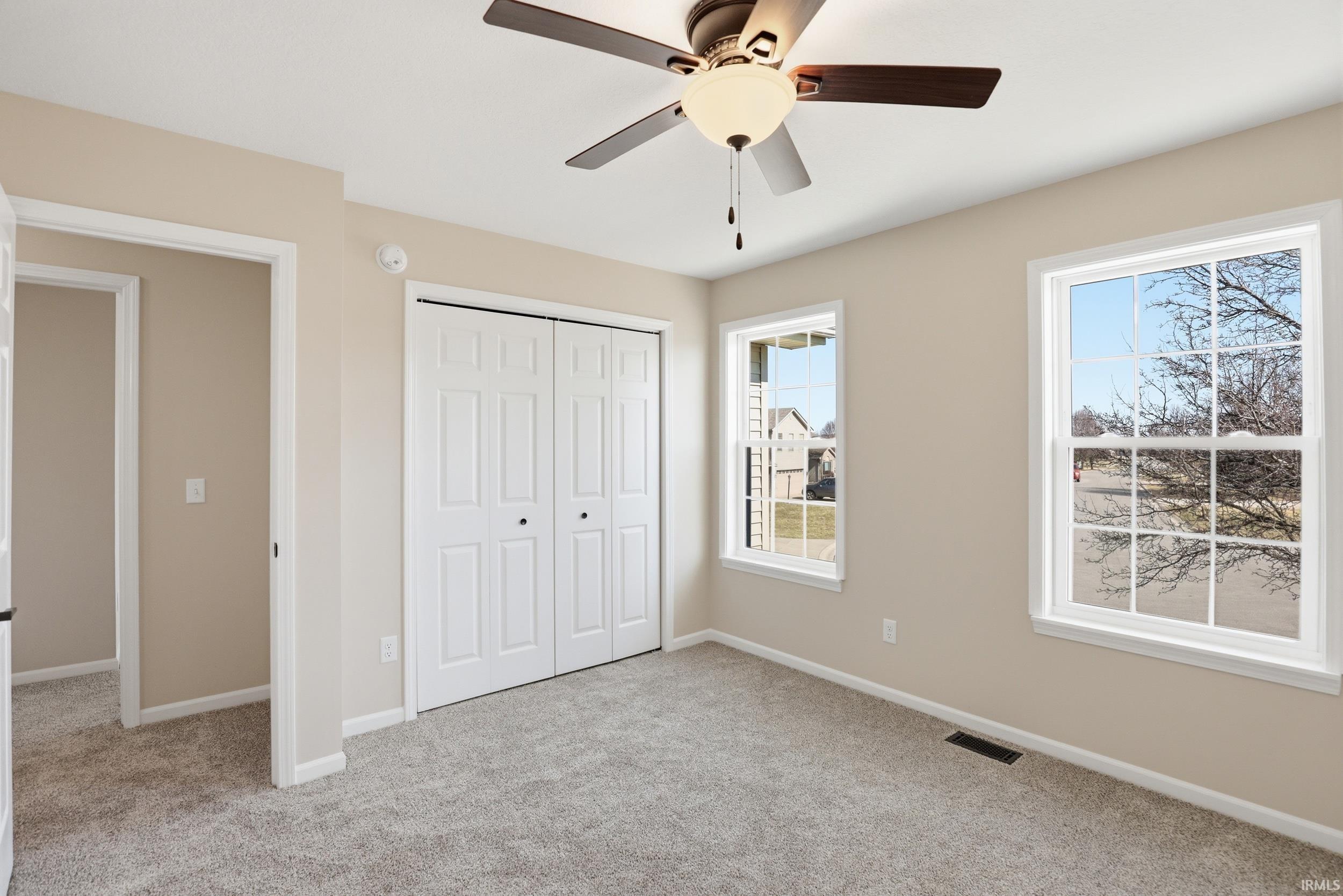 Unfurnished bedroom featuring a closet, light colored carpet, and ceiling fan