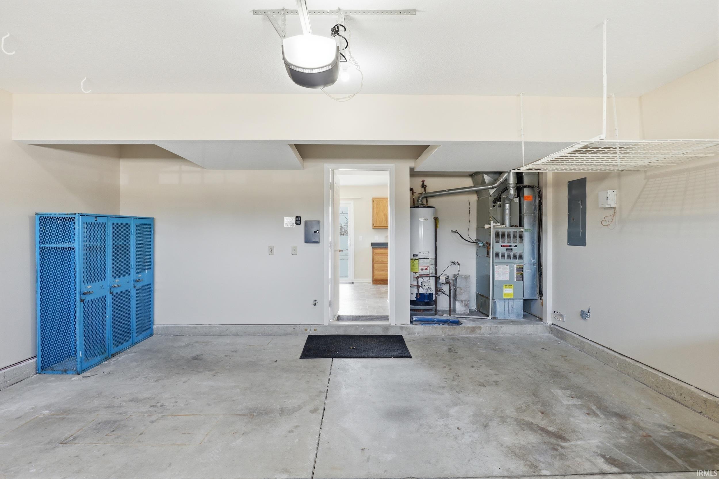 Garage with heating unit, gas water heater, electric panel, and a garage door opener