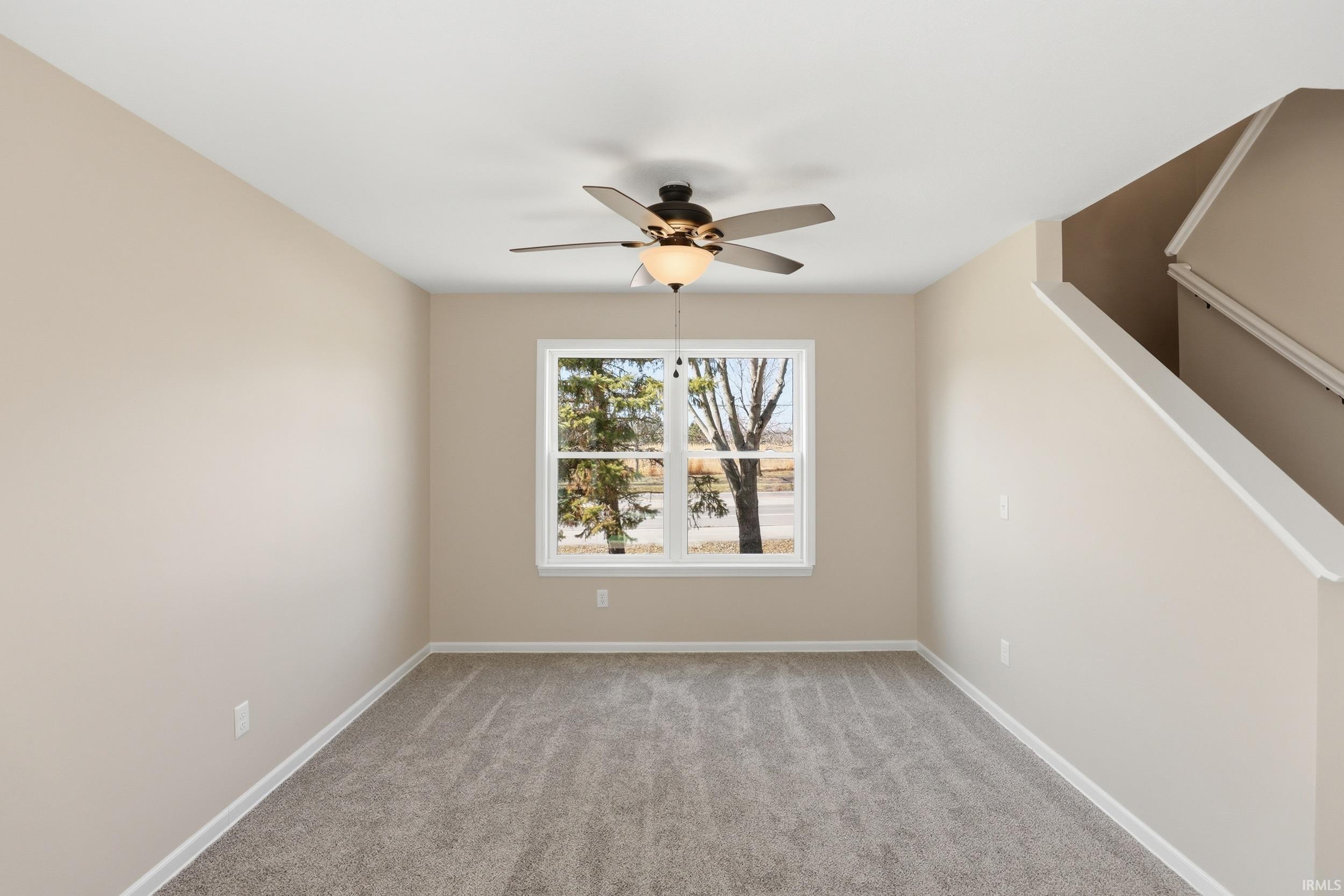 Empty room with light colored carpet and a ceiling fan