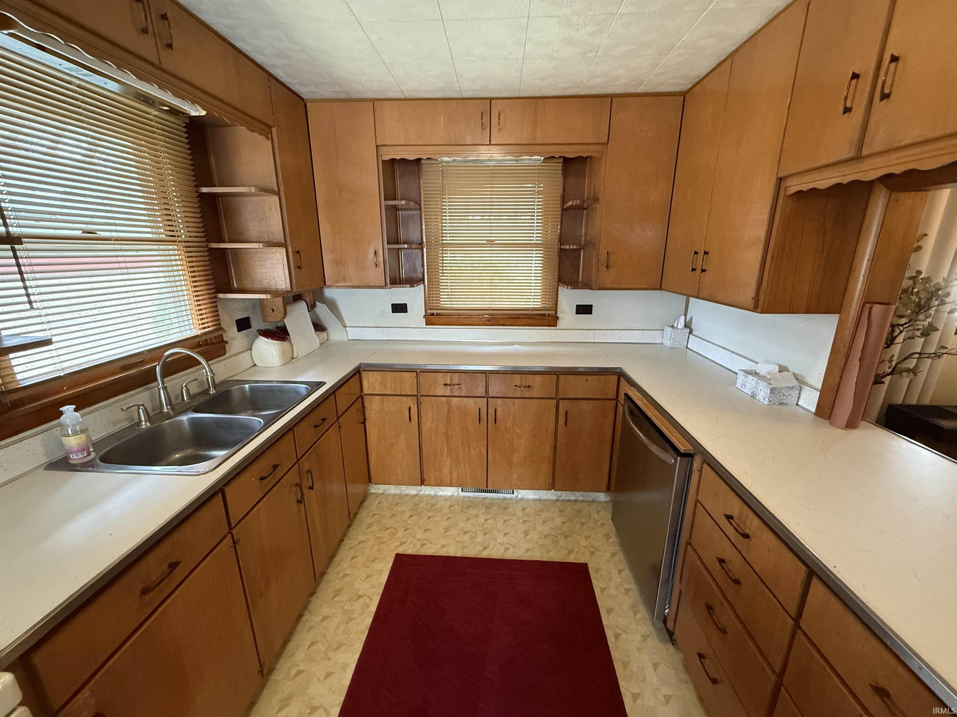 Kitchen featuring wood finish cabinets, open shelves, light countertops, light flooring, and dishwasher