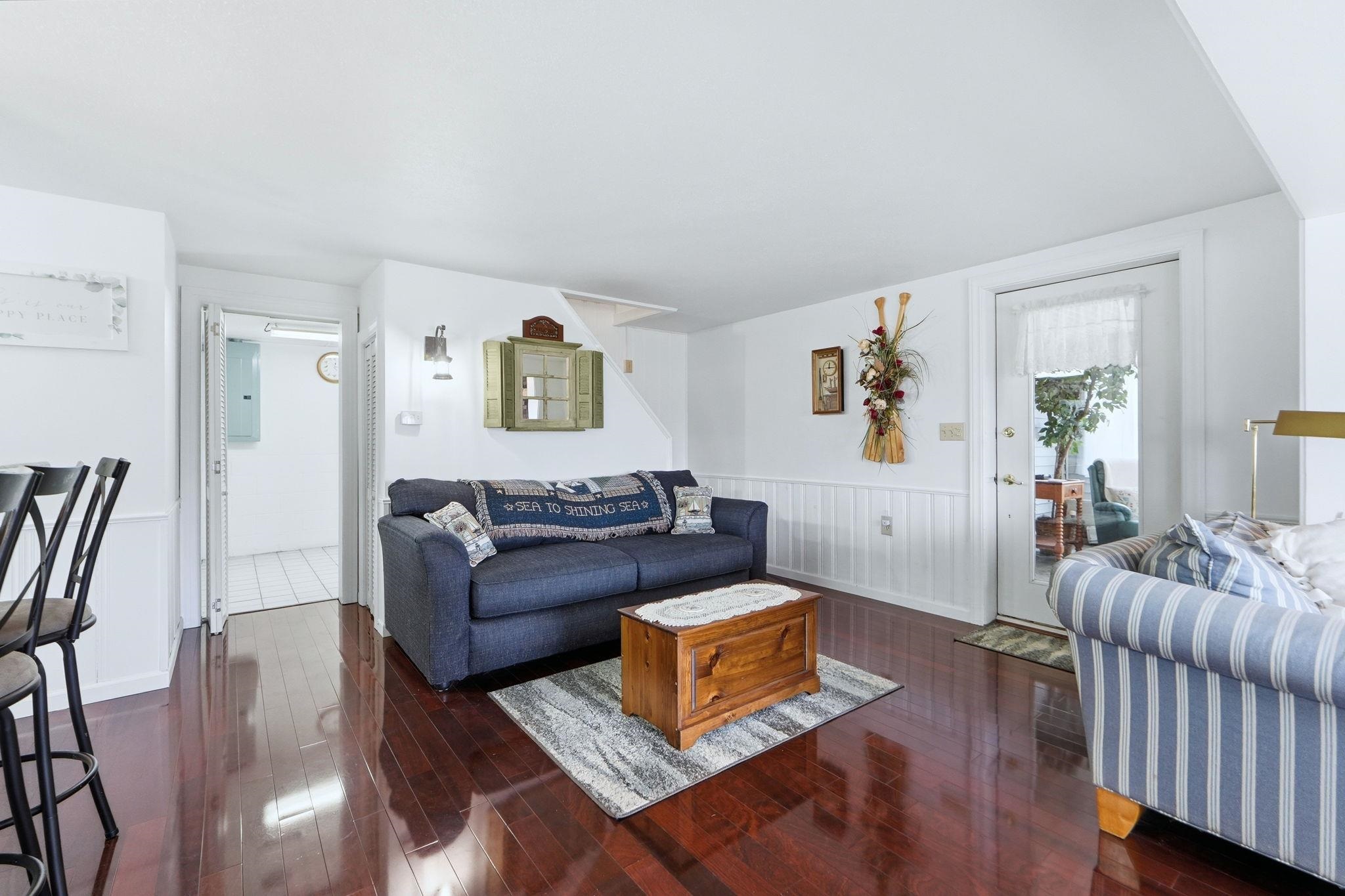 Living area featuring a wainscoted wall, dark wood-style floors, and electric panel