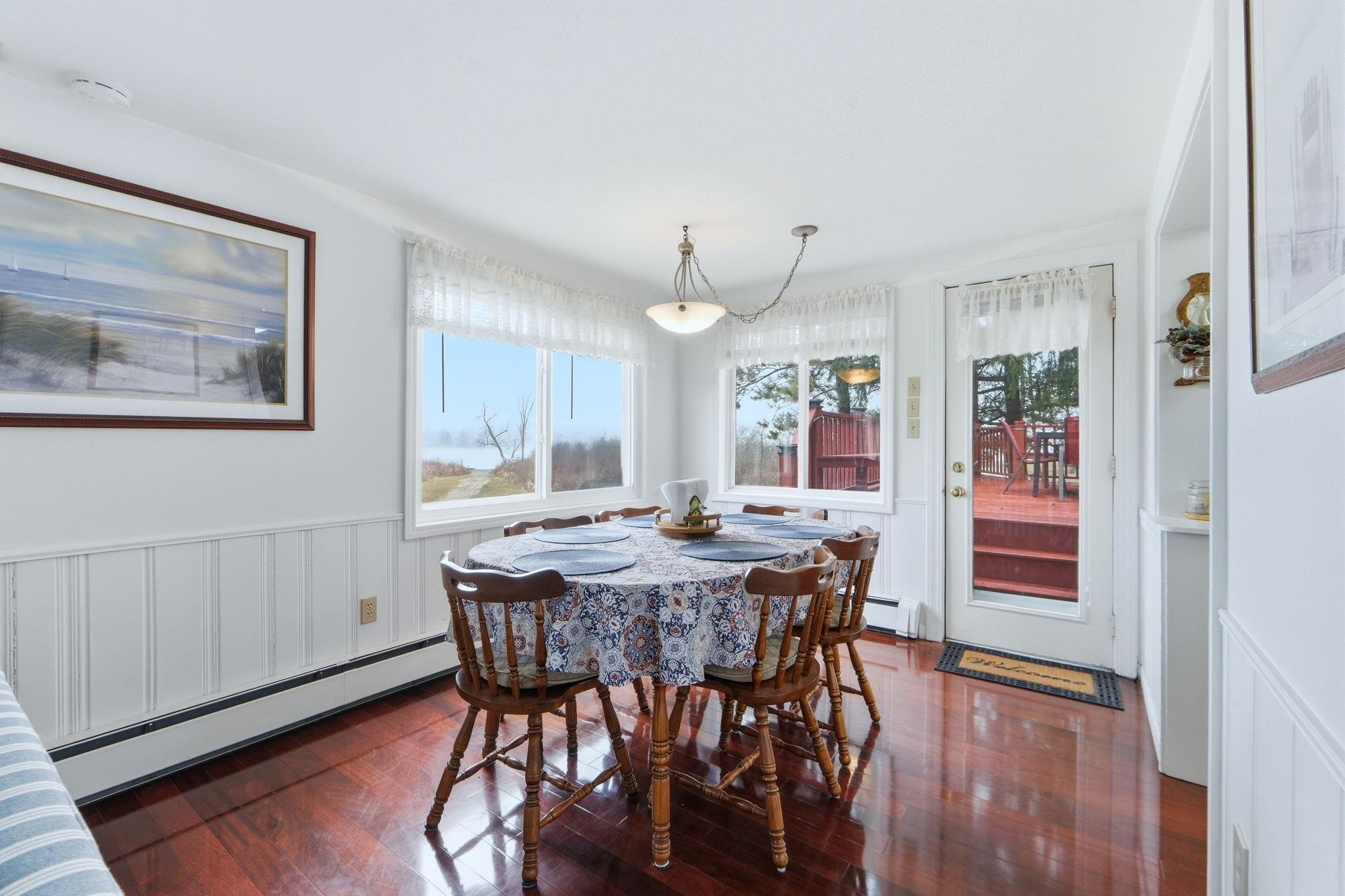 Dining area featuring a wainscoted wall, a baseboard radiator, dark wood-style floors, plenty of natural light, and a decorative wall