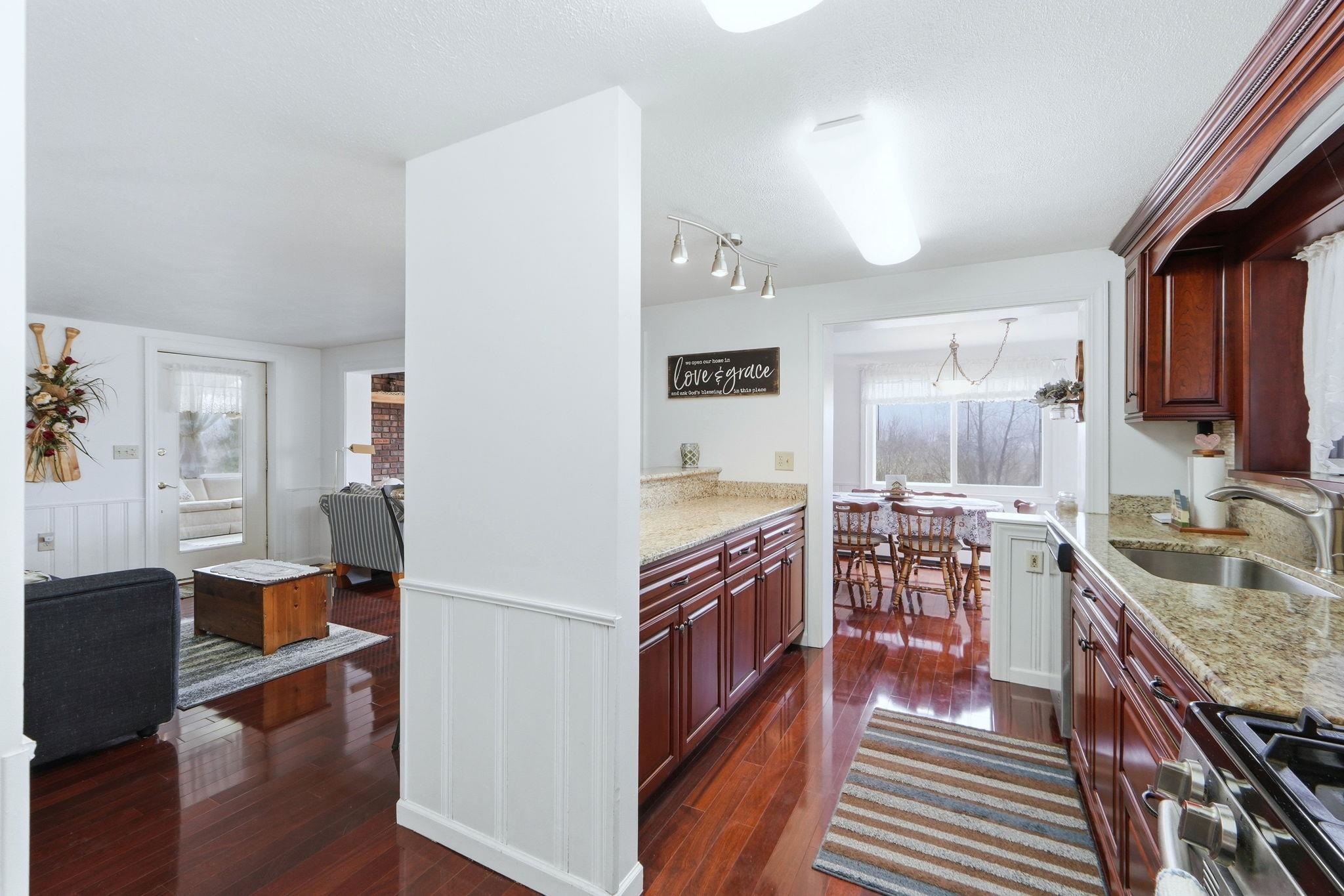 Kitchen with stainless steel appliances, light stone countertops, dark wood-style flooring, a wainscoted wall, and a decorative wall