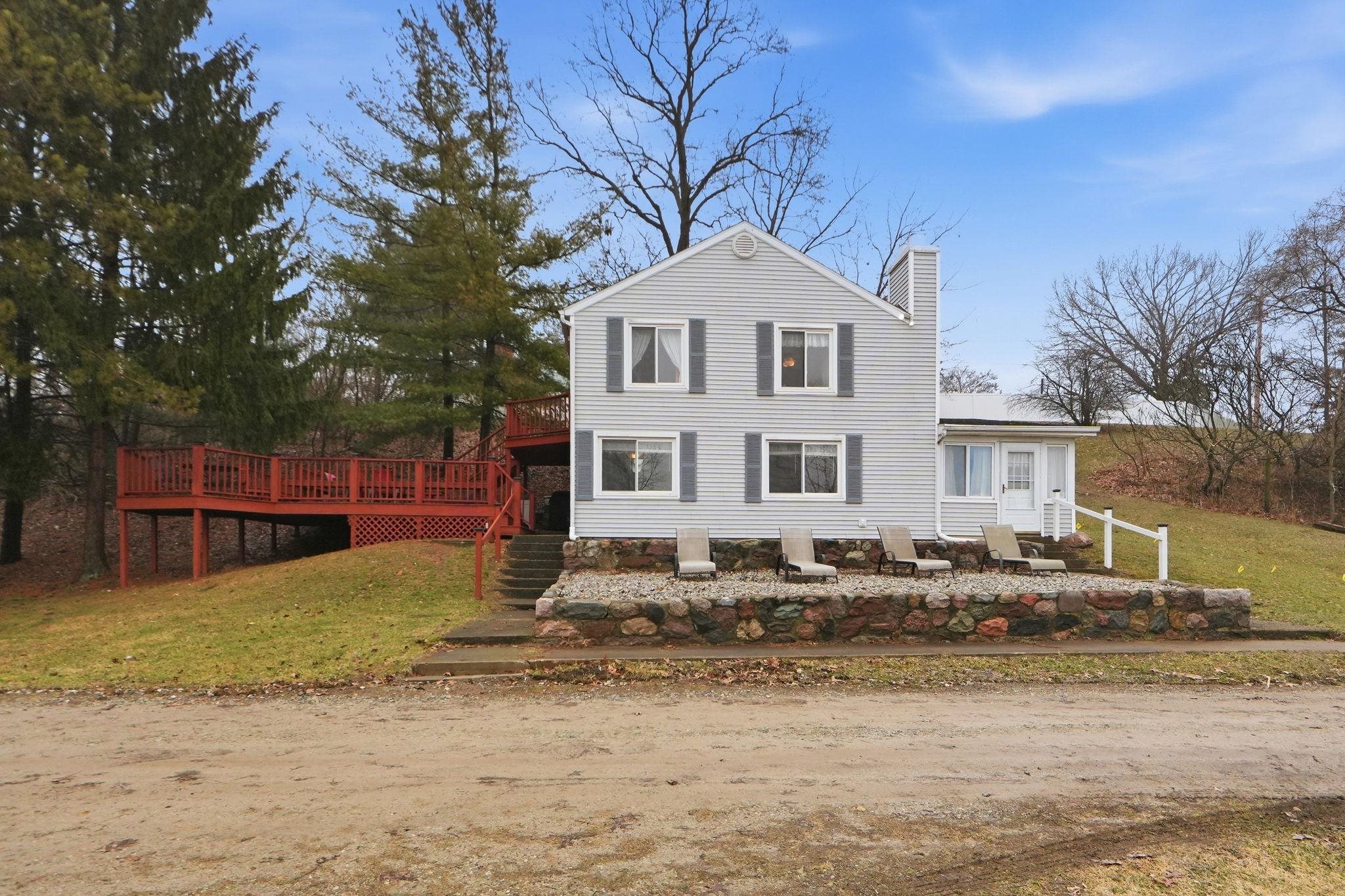 Traditional-style house with a front yard, a chimney, and a wooden deck