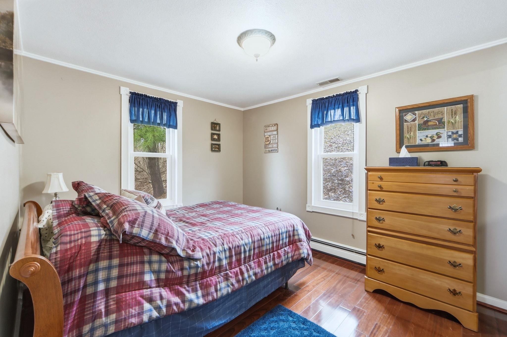 Bedroom with hardwood / wood-style flooring, baseboard heating, multiple windows, and ornamental molding