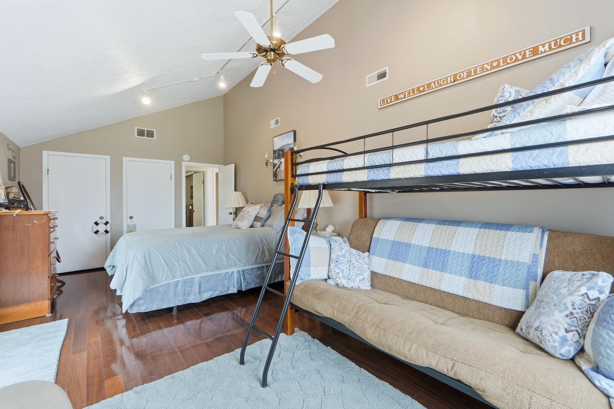Bedroom featuring vaulted ceiling, dark wood-type flooring, and ceiling fan