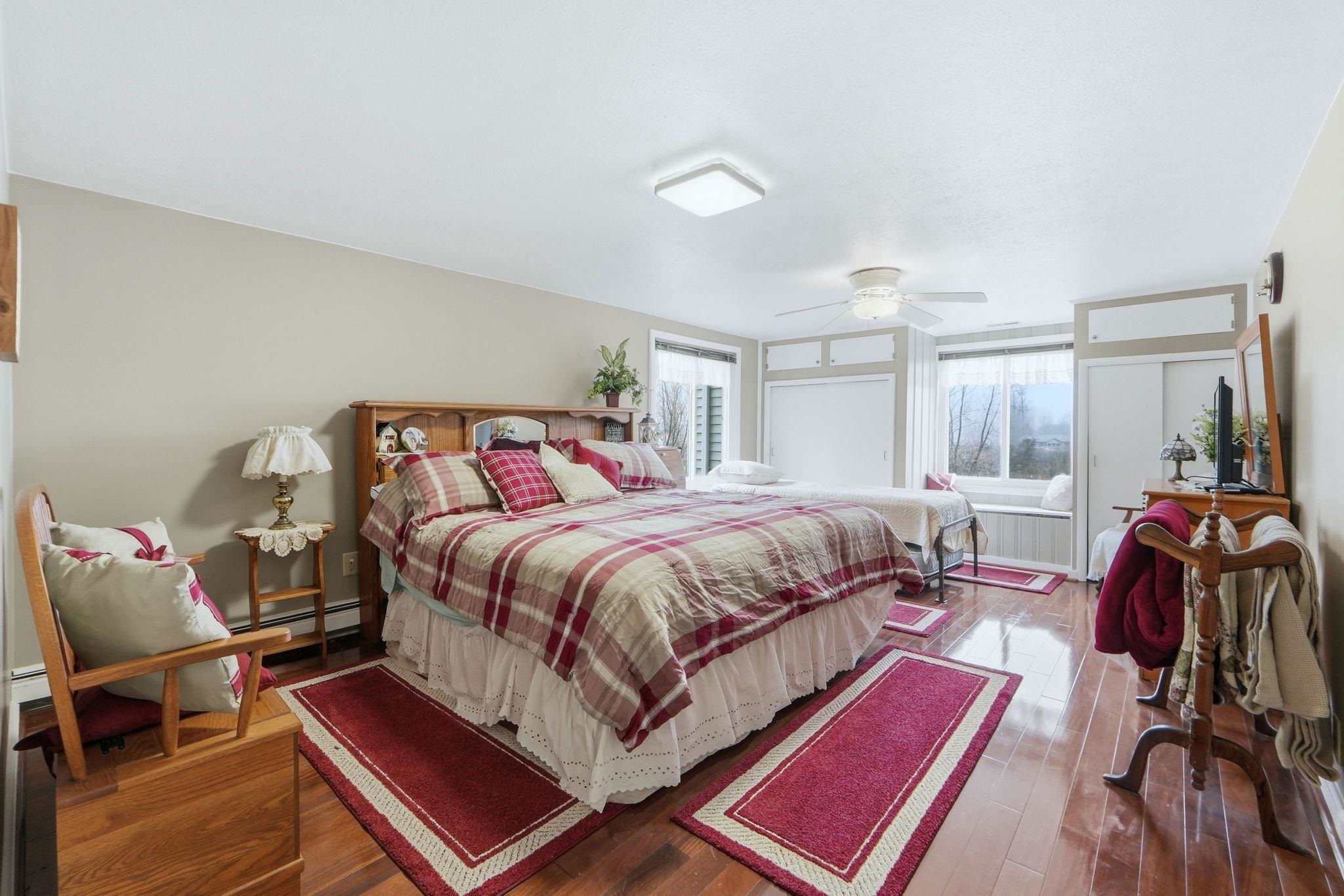 Bedroom with wood finished floors, a baseboard radiator, and a ceiling fan