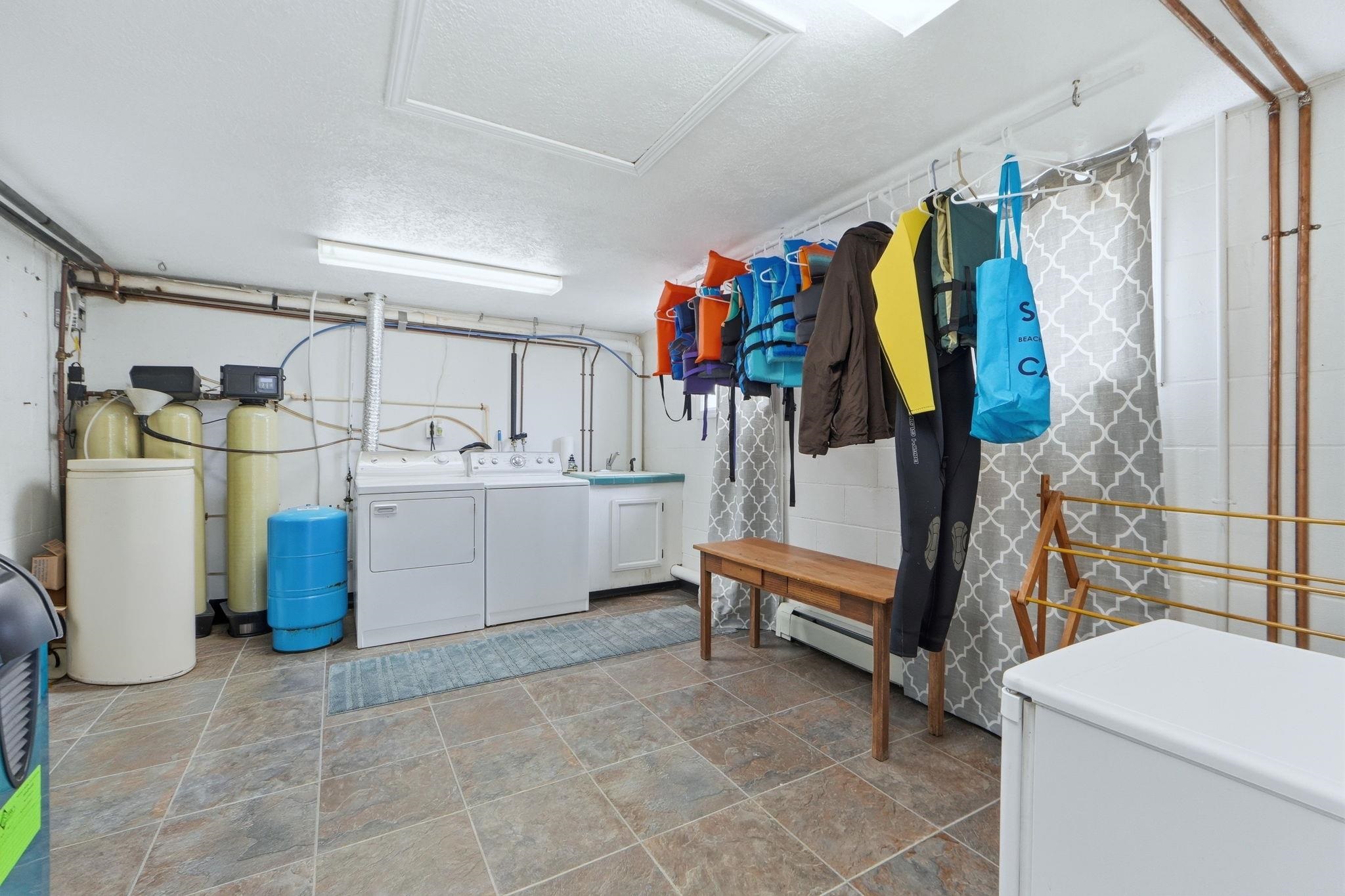 Laundry area with washer and clothes dryer, a textured ceiling, stone finish floors, a baseboard heating unit, and concrete block wall
