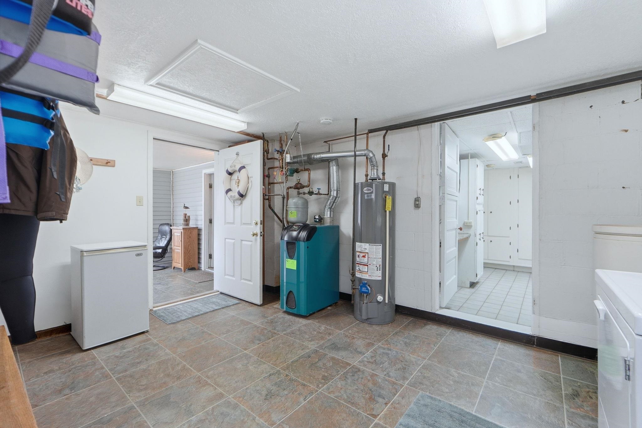Basement with gas water heater, a heating unit, washer and clothes dryer, light stone finish floors, and a textured ceiling
