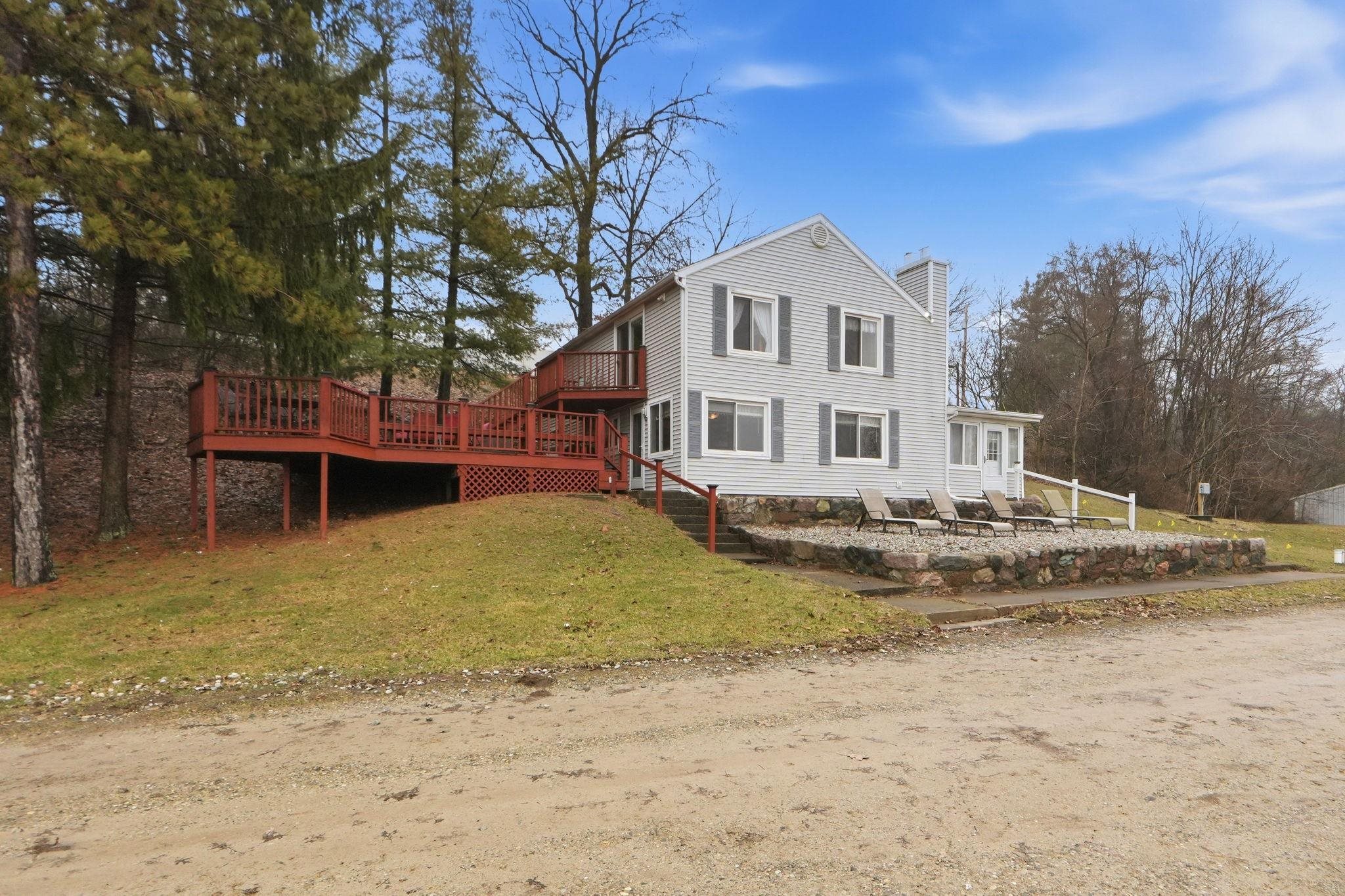 View of front of house with a chimney, a front lawn, and a wooden deck