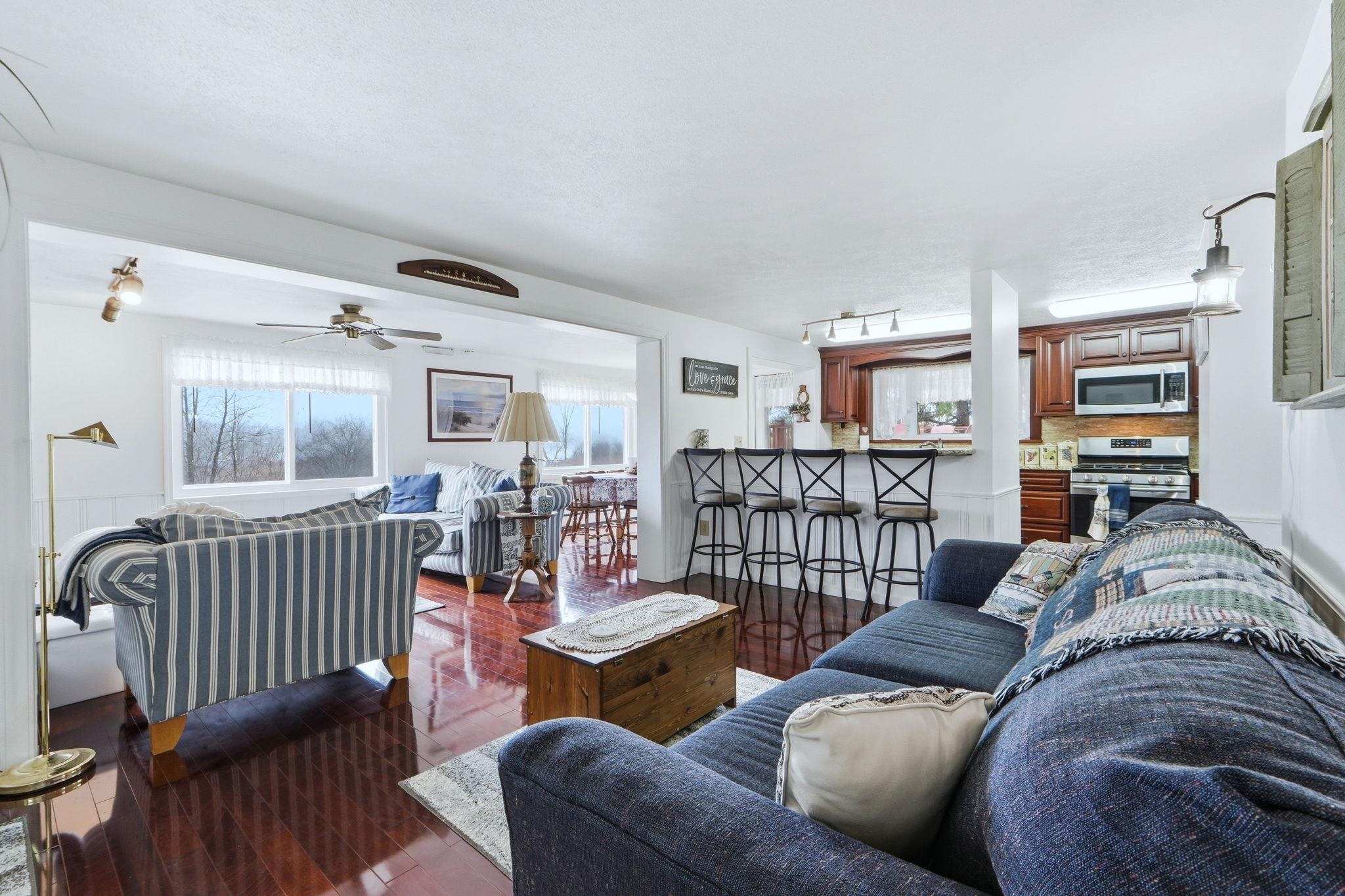 Living area featuring plenty of natural light, a ceiling fan, and dark wood-type flooring