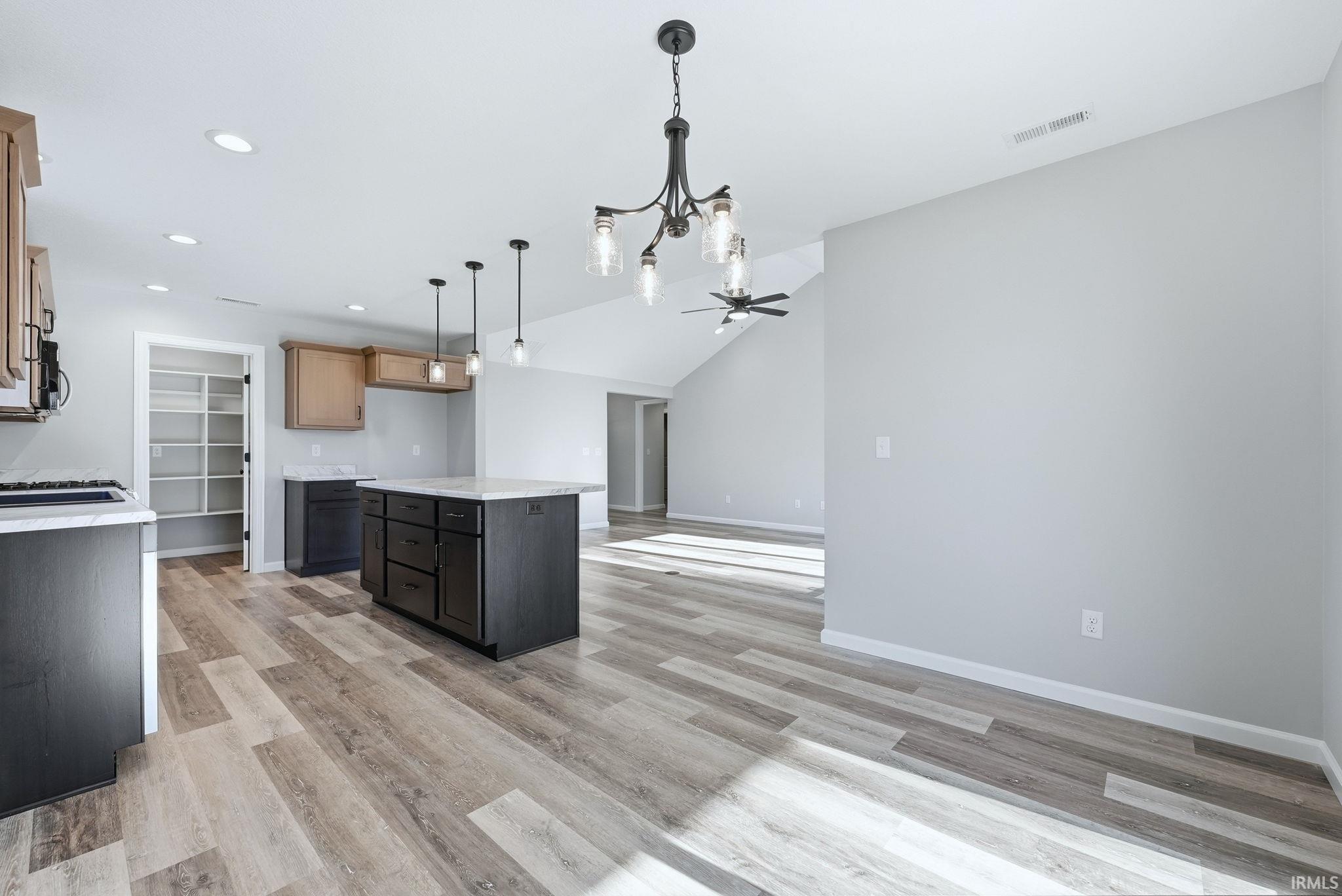 Kitchen featuring a center island, light wood-type flooring, open floor plan, lofted ceiling, and hanging lights