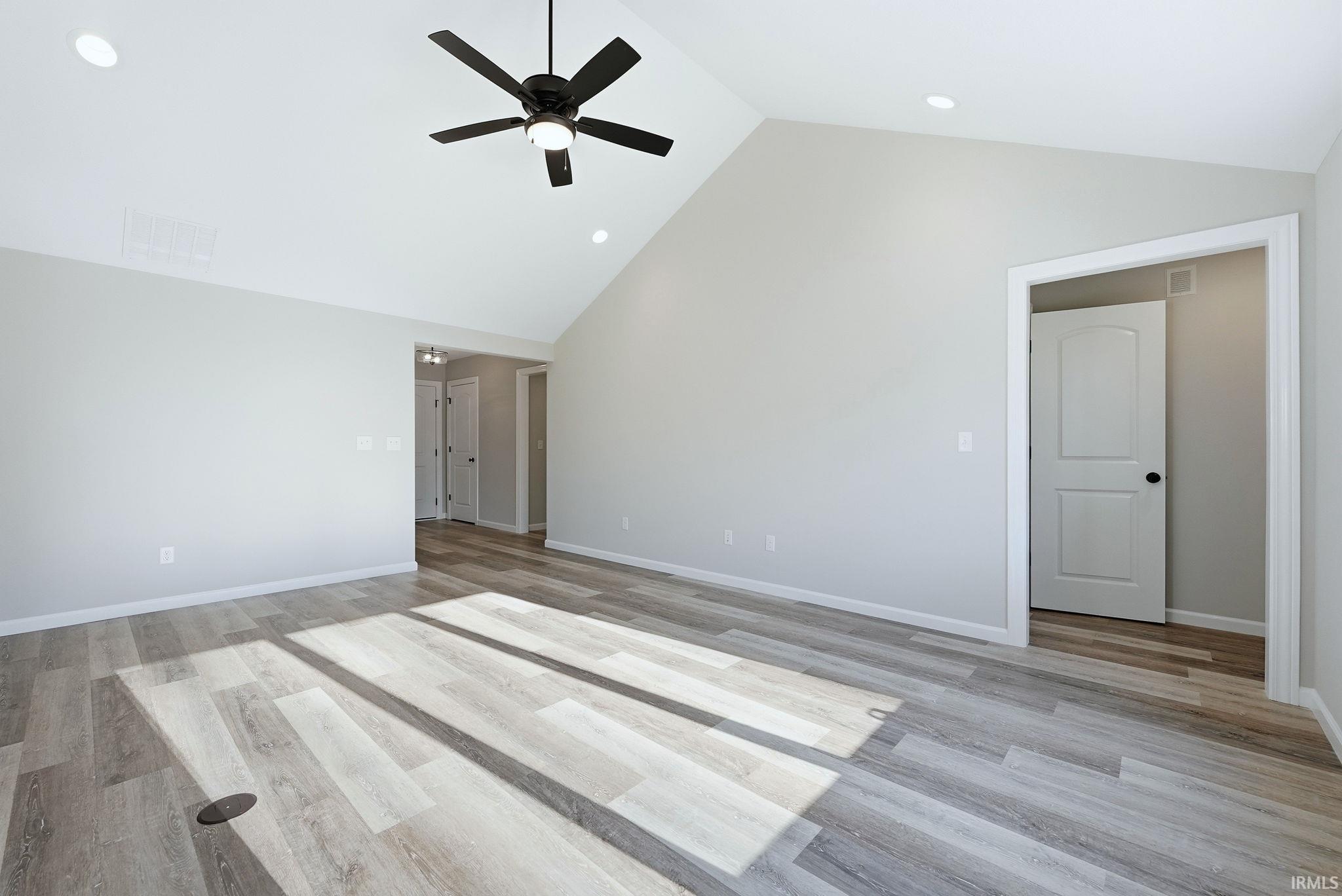 Empty room featuring ceiling fan, a high ceiling, light wood-style flooring, and recessed lighting