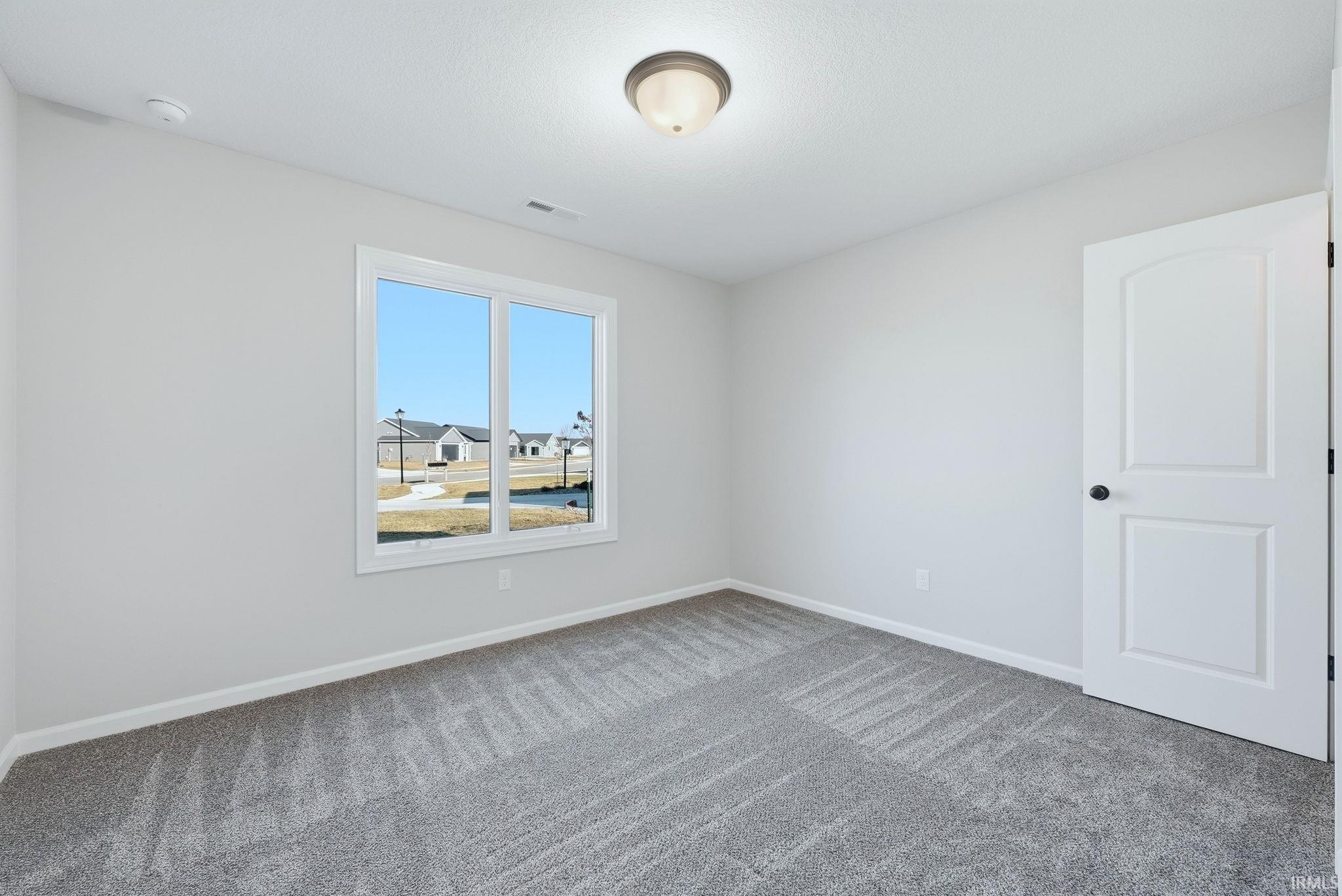 Empty room featuring light colored carpet and baseboards