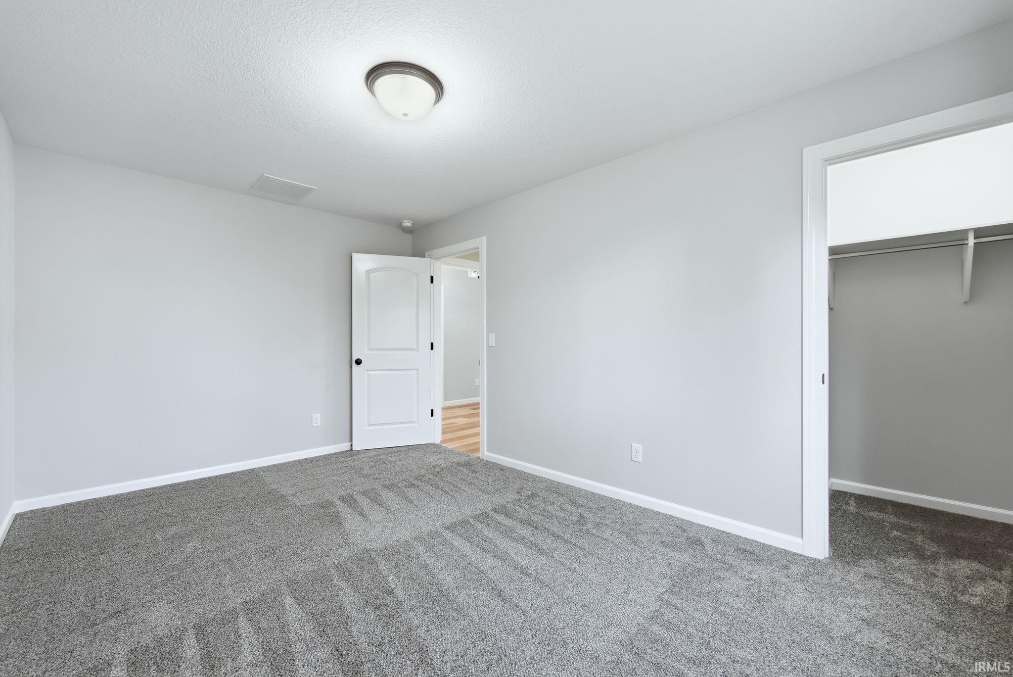 Unfurnished bedroom featuring a walk in closet and carpet flooring