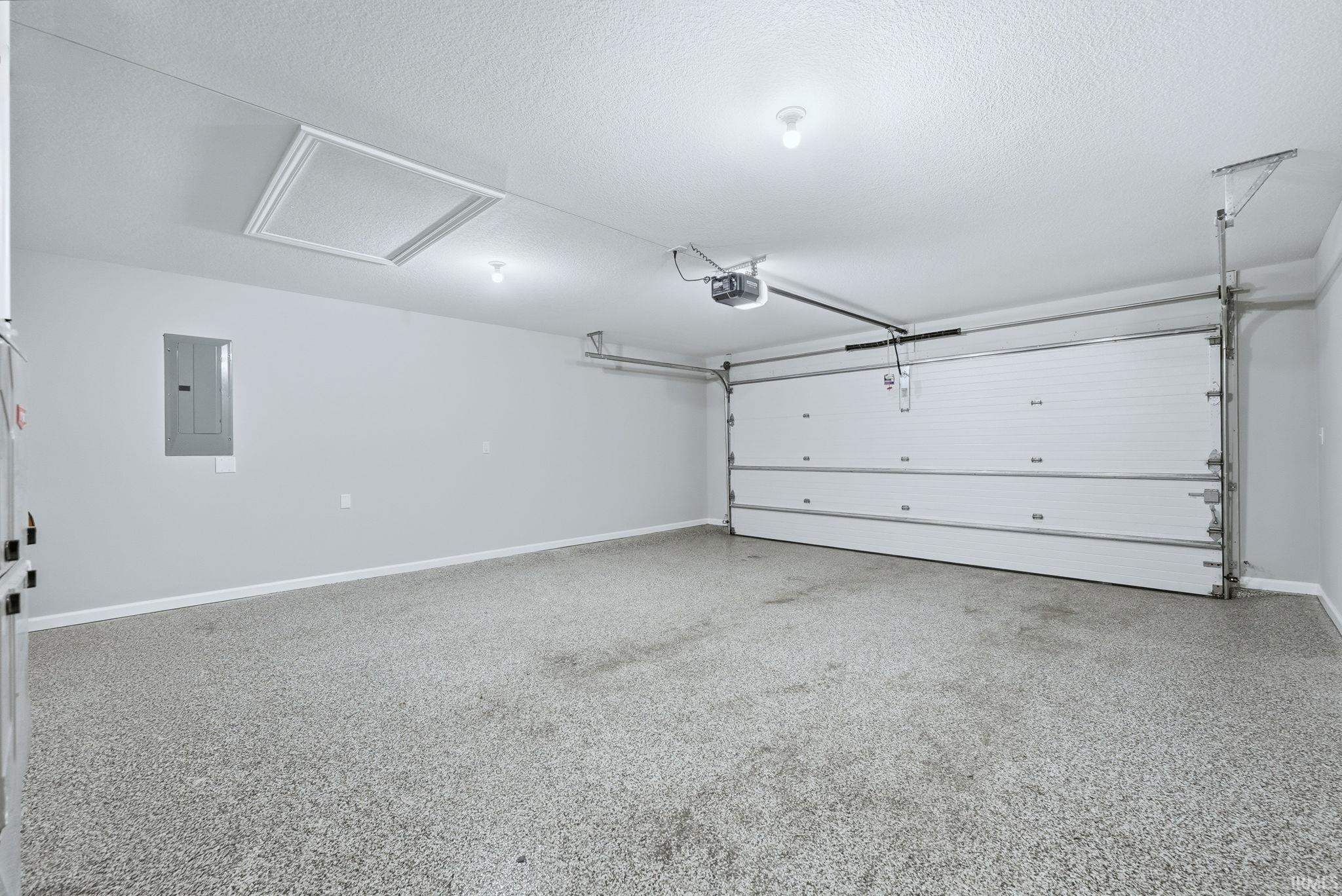 Garage featuring electric panel and baseboards