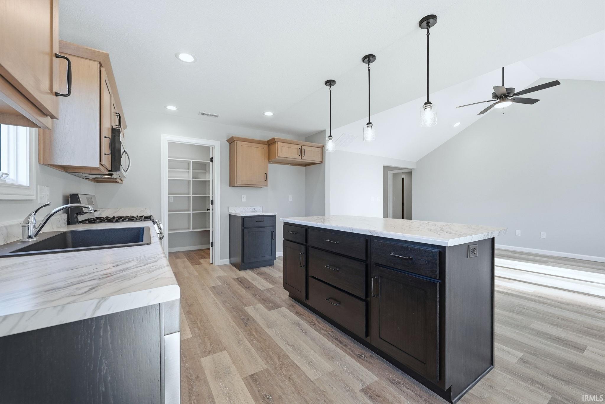 Kitchen with a center island, light countertops, light wood-style floors, gas range, and hanging light fixtures