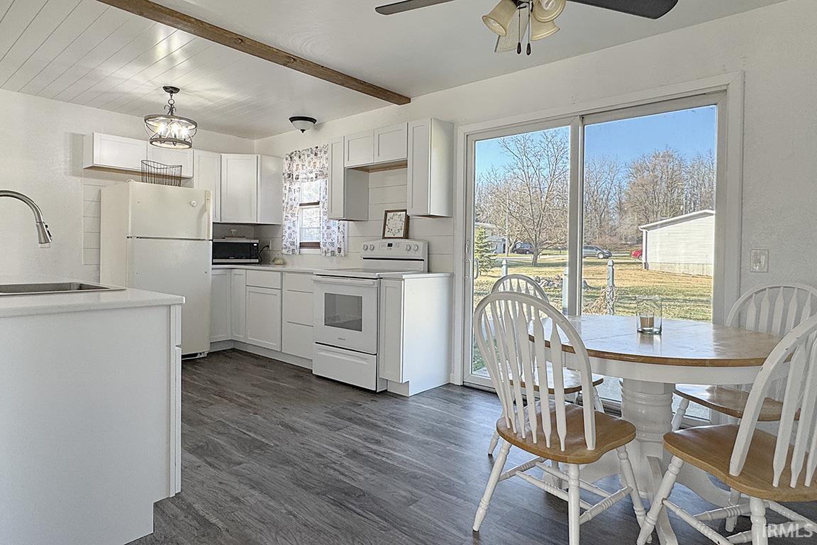 Kitchen featuring white cabinetry, white appliances, light countertops, and beam ceiling
