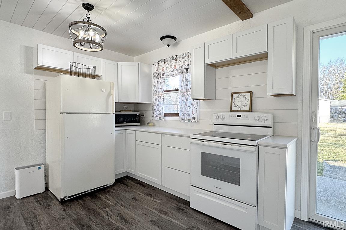 Kitchen featuring white appliances, light countertops, white cabinetry, and dark wood-style floors