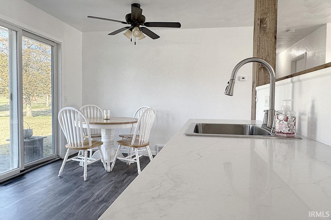 Kitchen with light stone countertops, ceiling fan, and dark wood finished floors