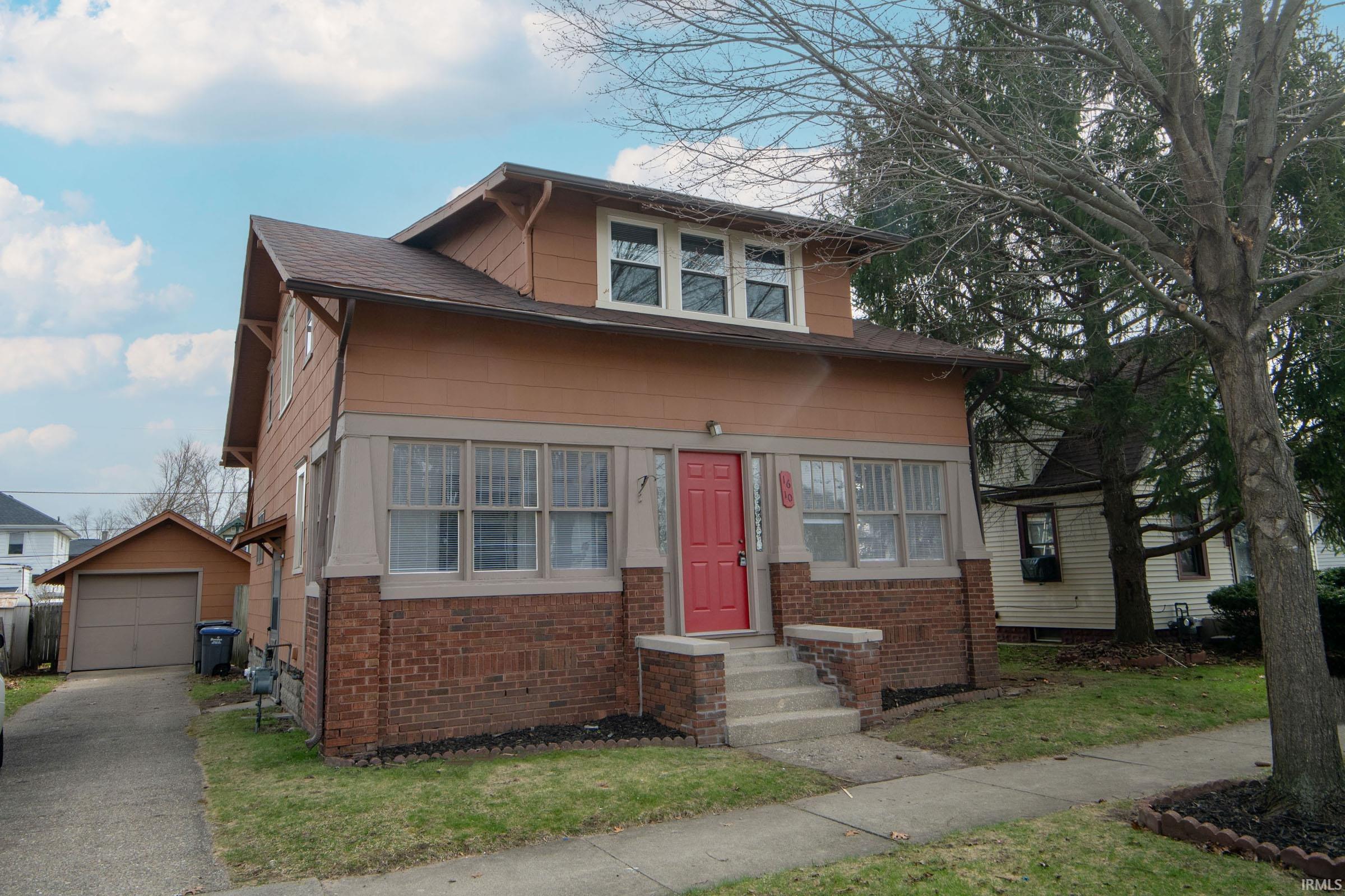 View of front of property featuring an outbuilding, brick siding, a garage, and entry steps