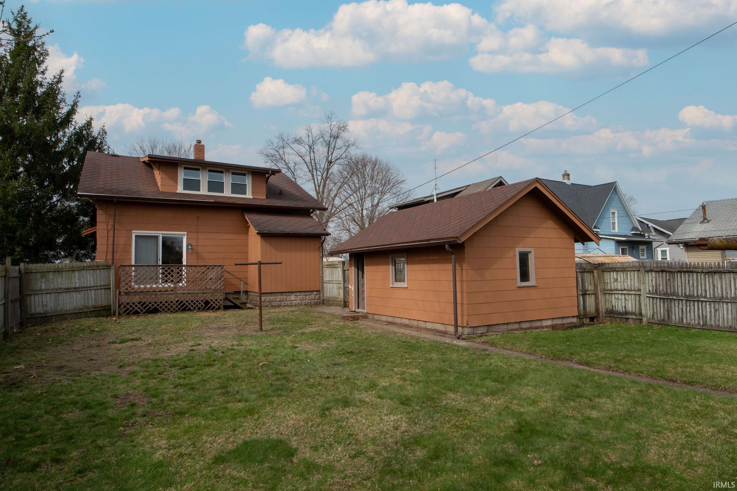 Rear view of property with a chimney, a fenced backyard, and a deck
