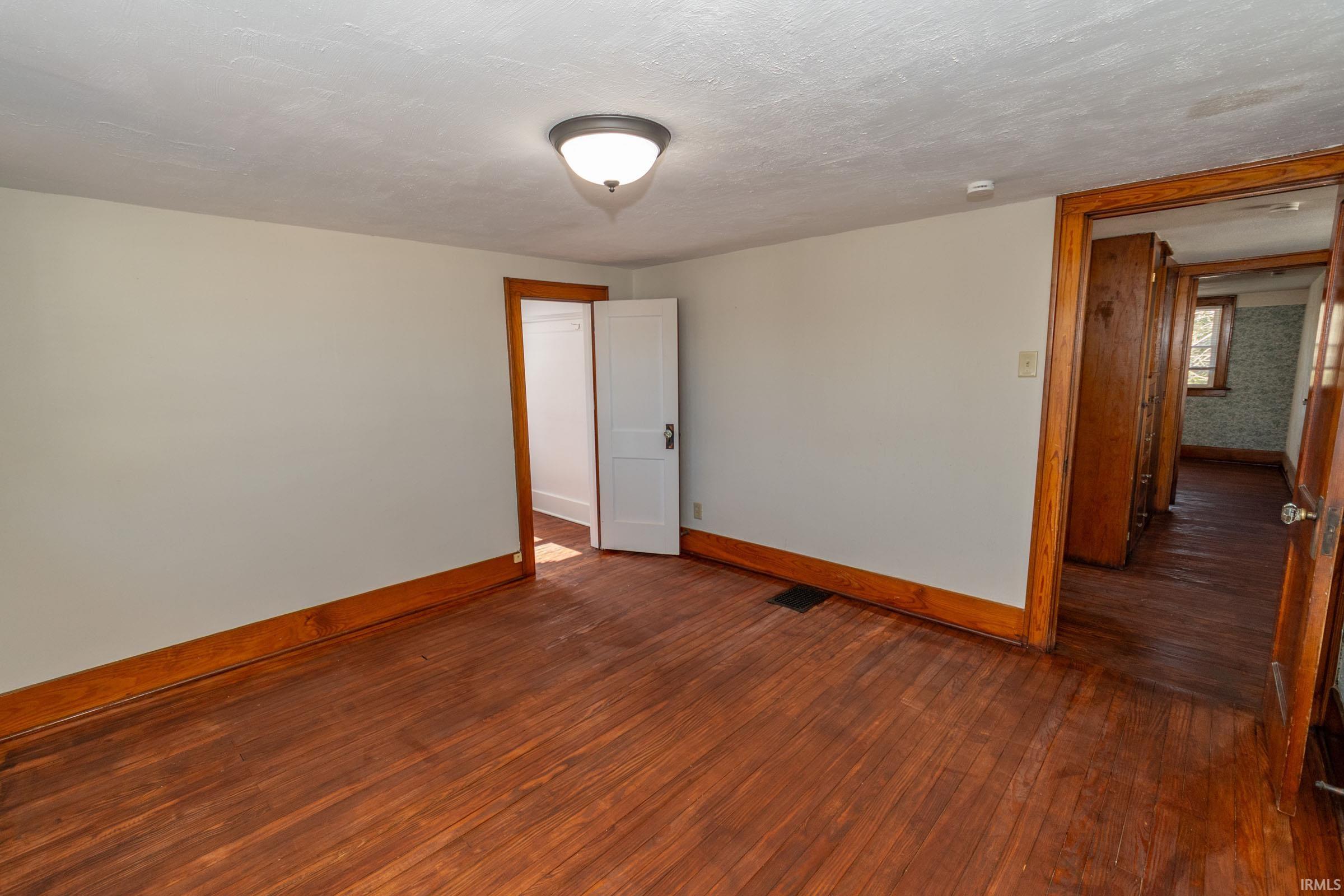 Spare room with wood-type flooring and baseboards