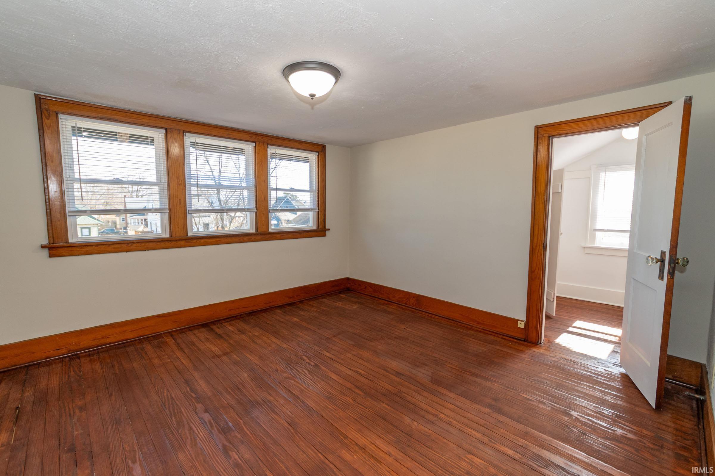 Empty room featuring dark wood-style flooring and plenty of natural light