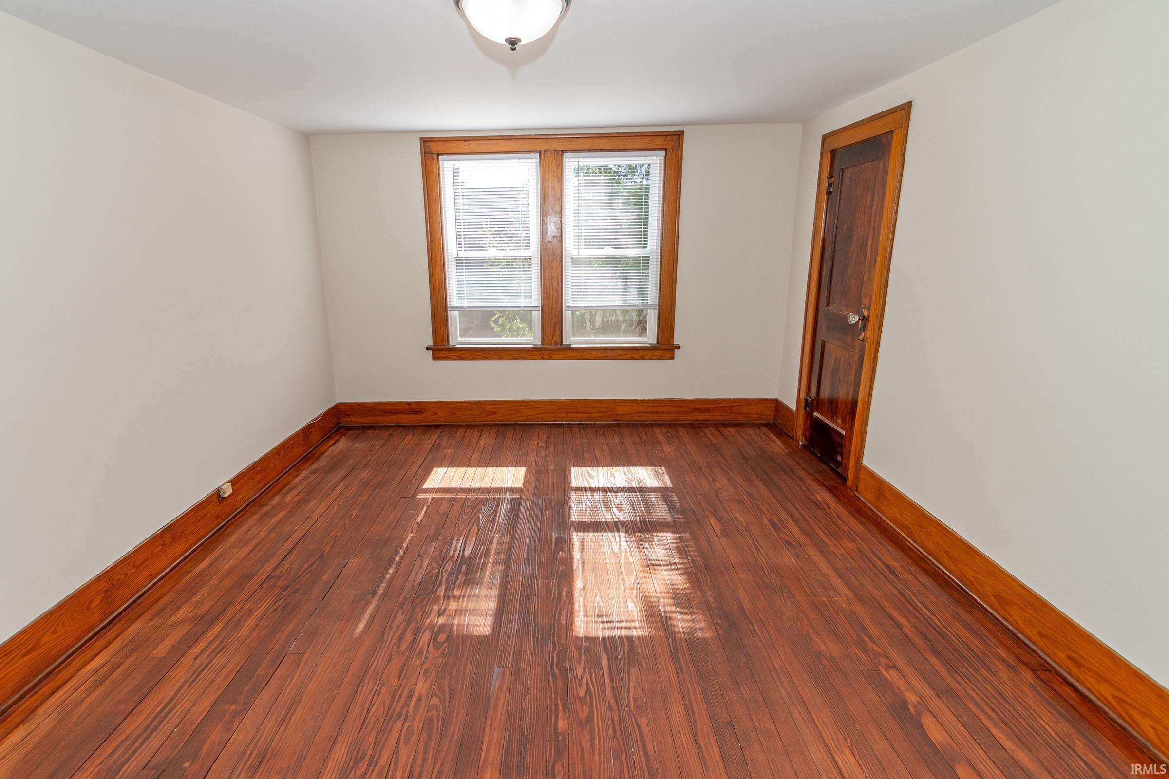 Empty room with dark wood finished floors and baseboards
