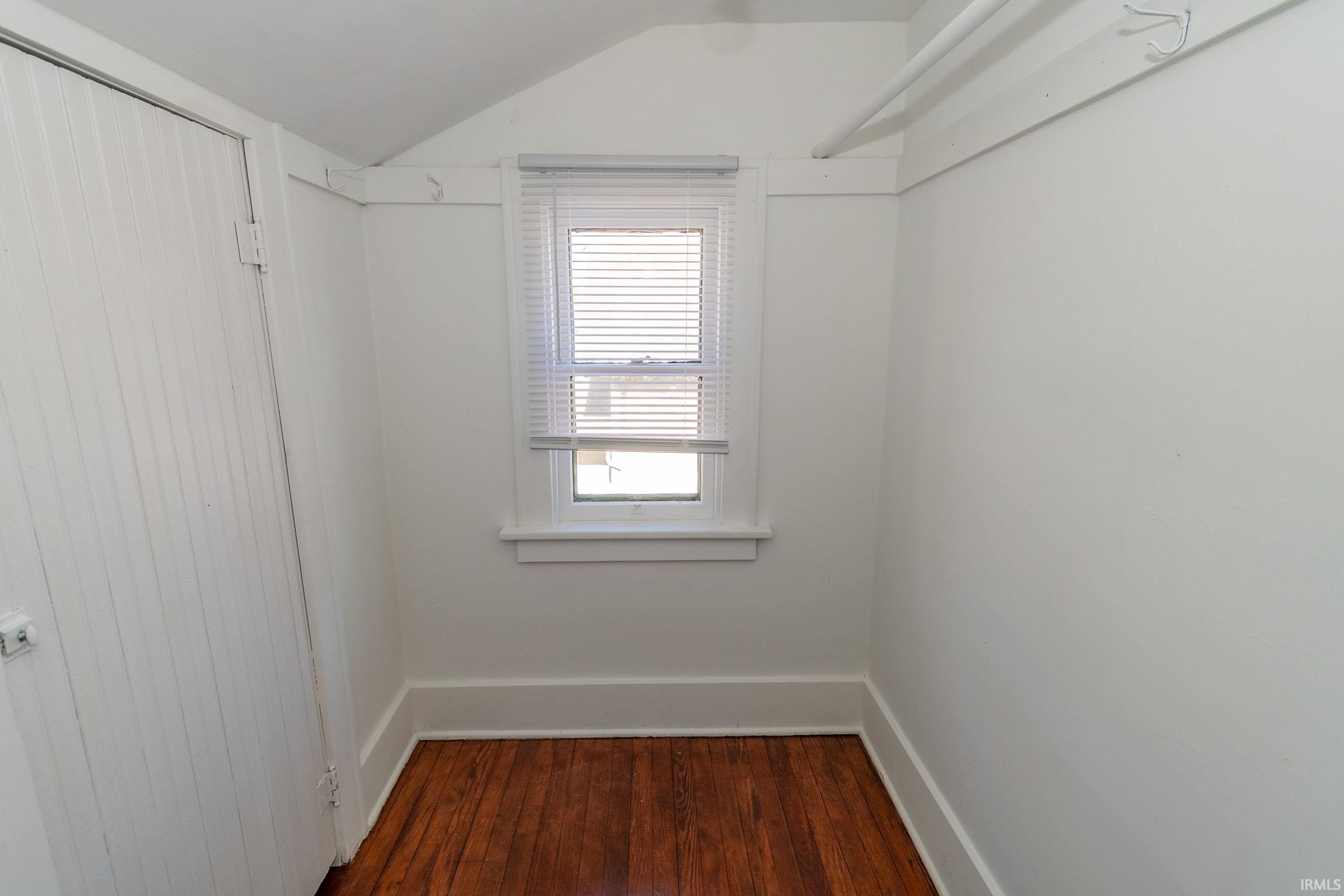 Spare room featuring lofted ceiling and dark wood-type flooring